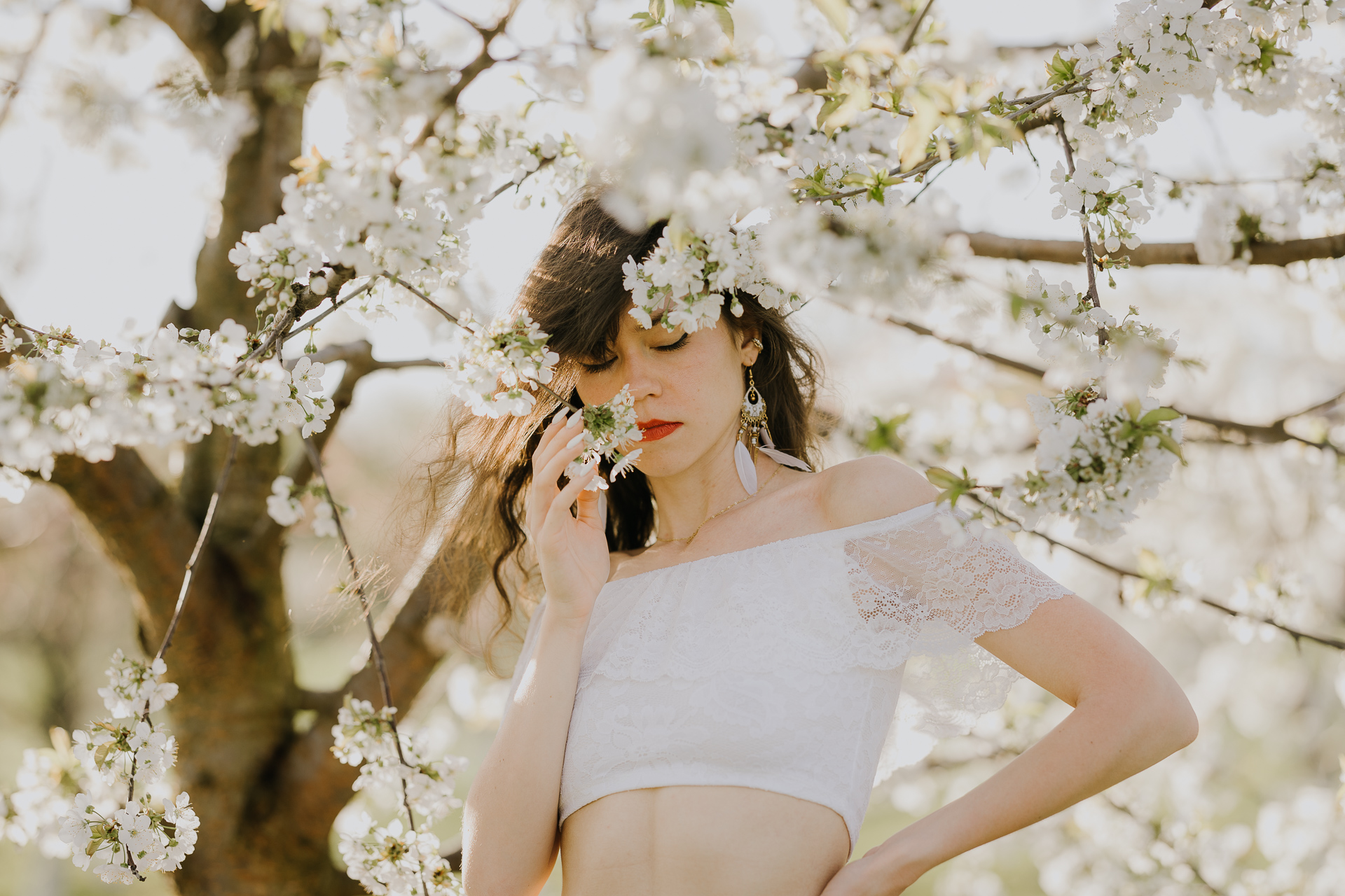 Zbliżenie twarzy modelki podczas sesji w kwitnącym sadzie jabłoniowym, profesjonalna fotografia kobieca, okolice Krakowa