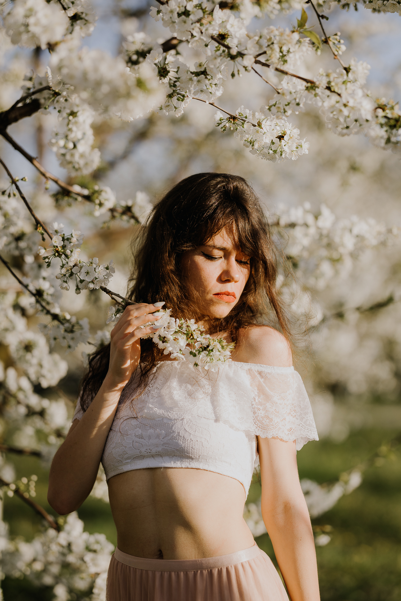 Portret modelki podczas sesji w kwitnącym sadzie jabłoniowym, profesjonalna fotografia kobieca, okolice Krakowa