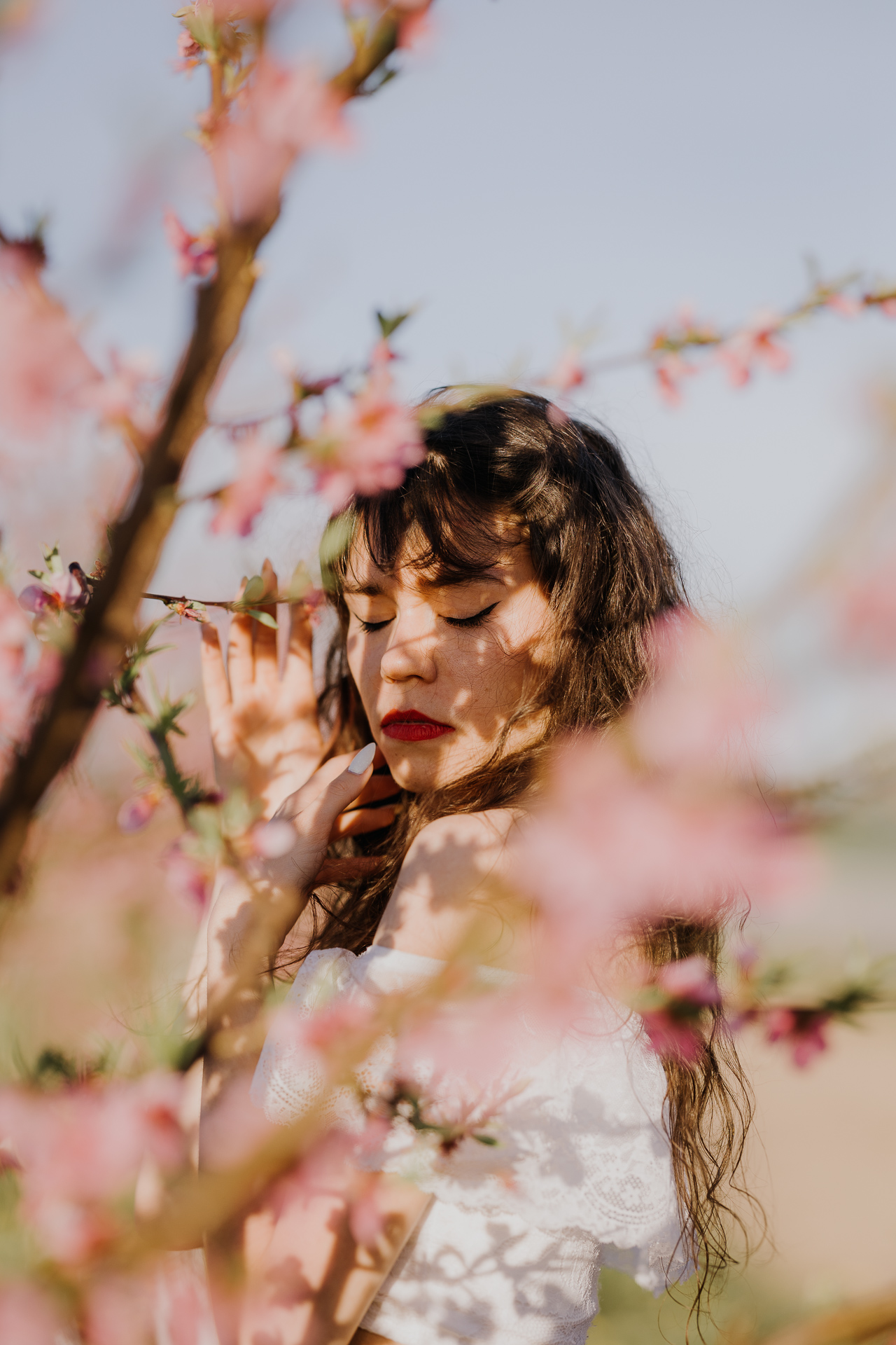 Portret kobiecy w kwitnącym sadzie pod Krakowem, modelka wśród brzoskwini w pełnym rozkwicie, wiosenna sesja fotograficzna