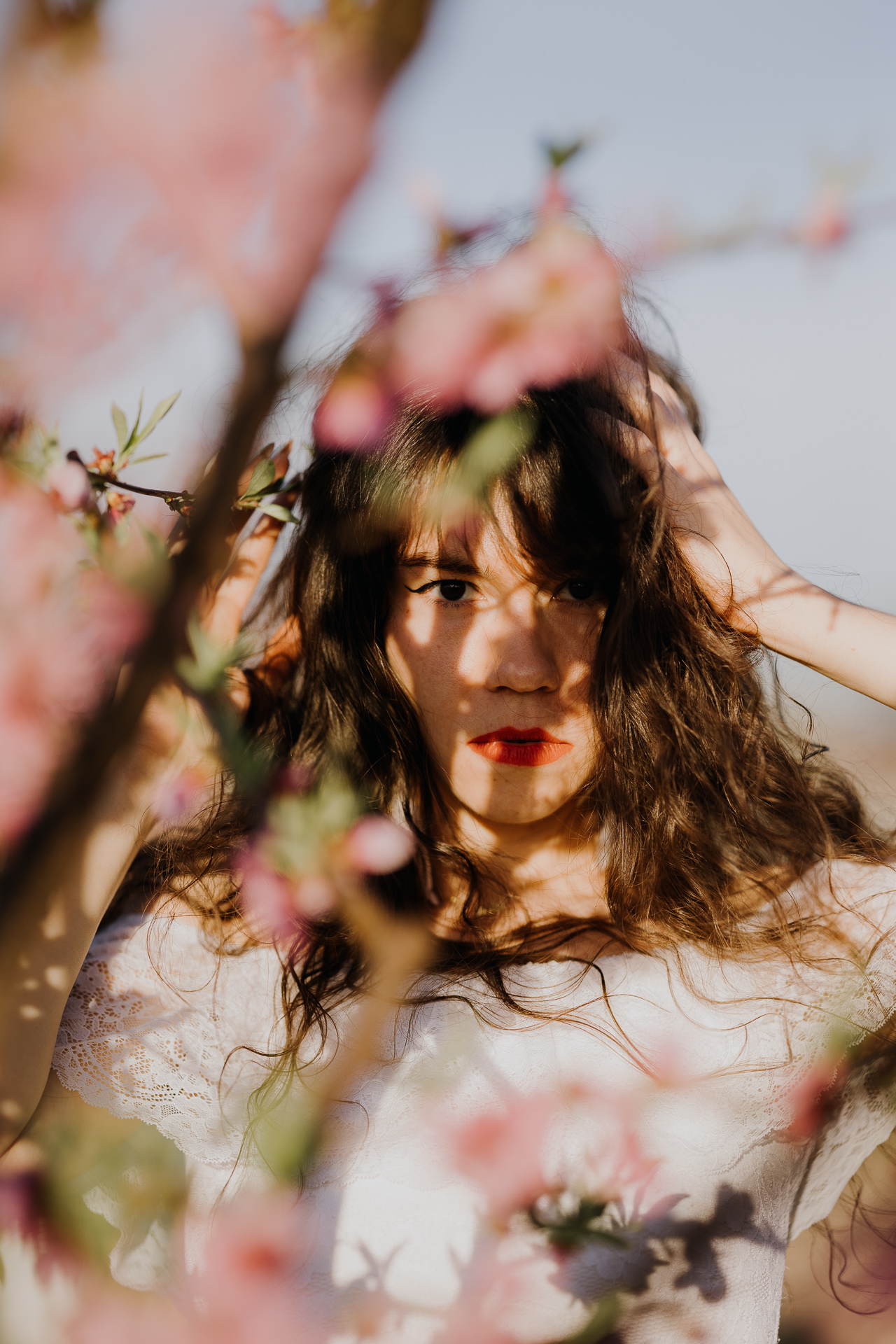 Portret kobiecy w kwitnącym sadzie pod Krakowem, modelka wśród brzoskwini w pełnym rozkwicie, wiosenna sesja fotograficzna