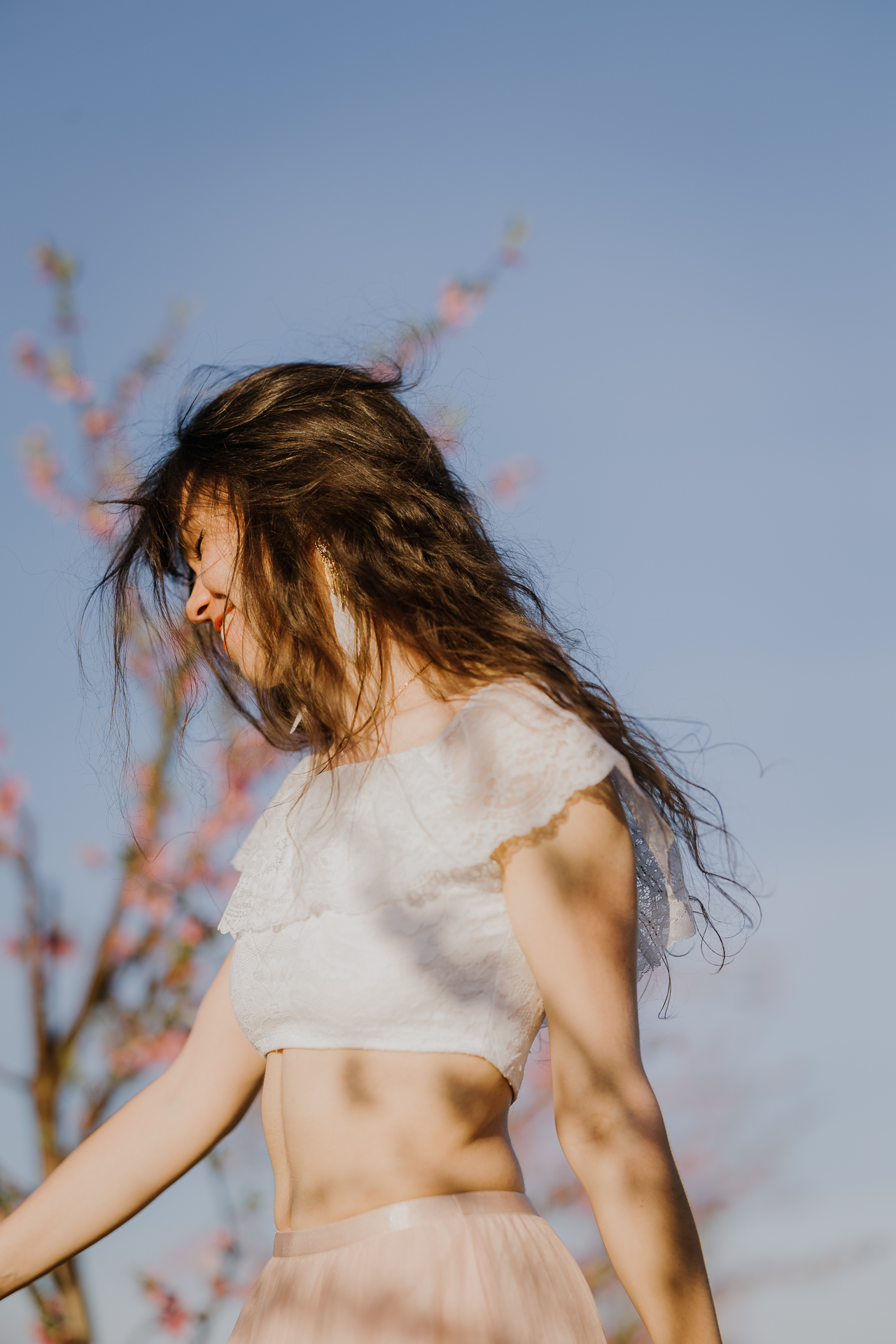 kobieta tańczy w kwitnącym sadzie pod Krakowem, modelka na tle brzoskwini w pełnym rozkwicie, wiosenna sesja fotograficzna