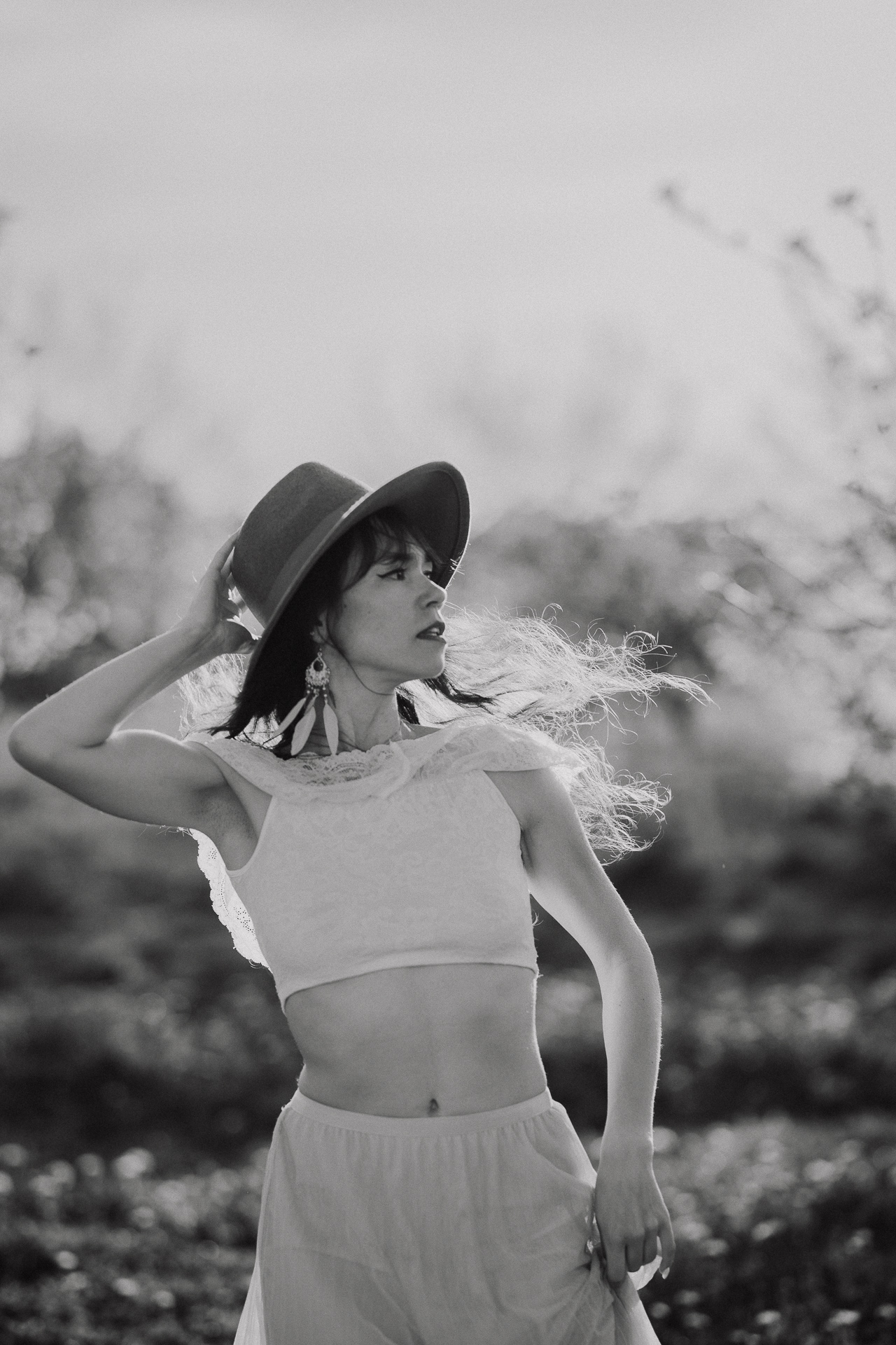 kobieta biegnie trzymając kapelusz w kwitnącym sadzie pod Krakowem, wiosenna sesja fotograficzna