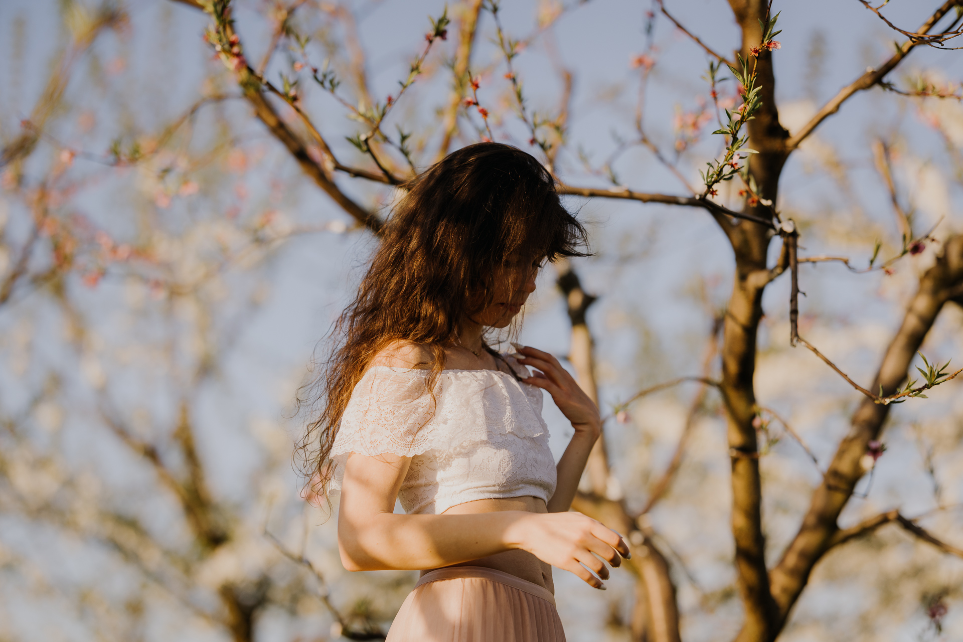 Kobieta przy drzewach owocowych w kwitnącym sadzie, wiosenna sesja kobieca
