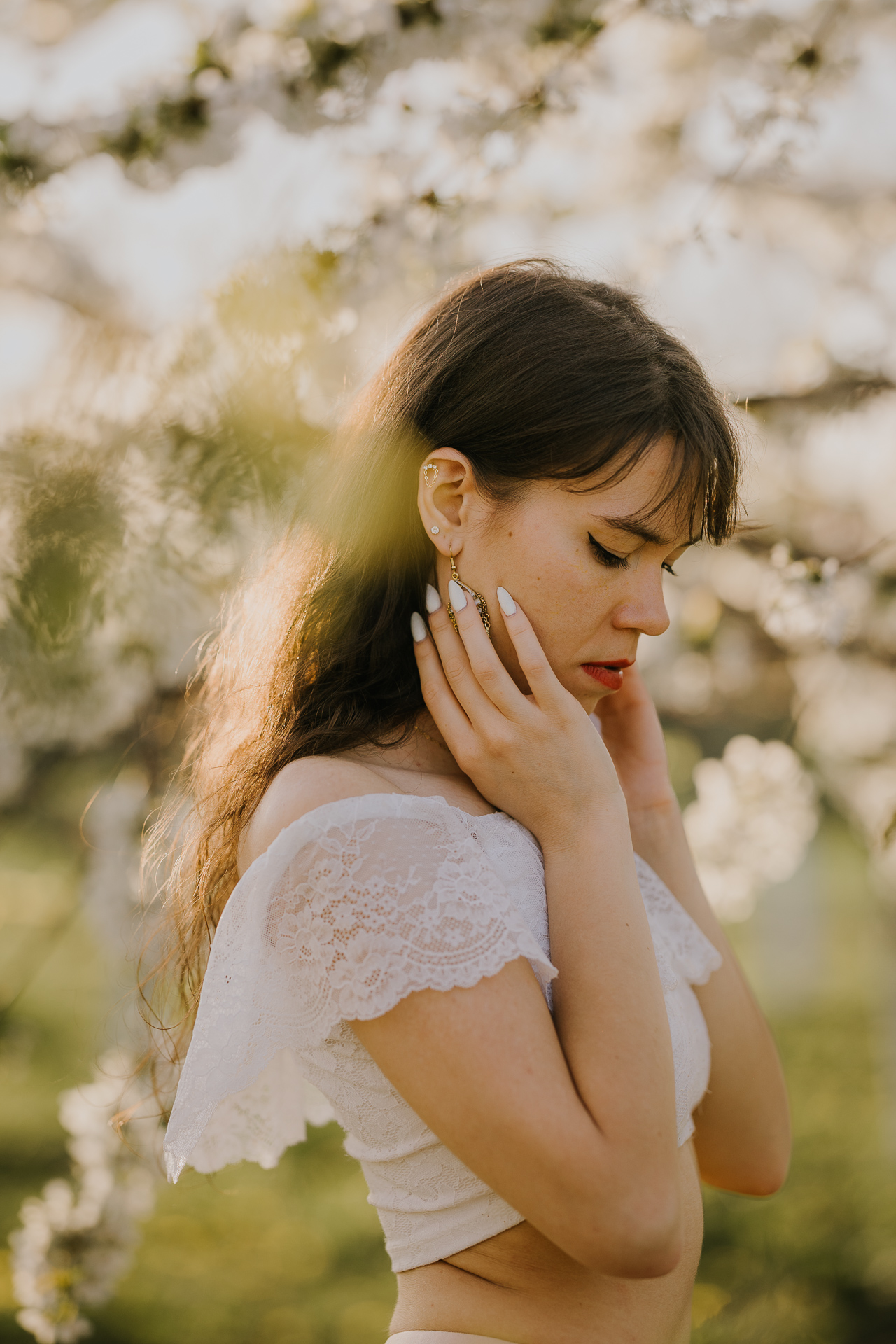 Detal z kobiecej sesji fotograficznej w sadzie, delikatne kwiaty jabłoni i dodatki, fotografia plenerowa Małopolska