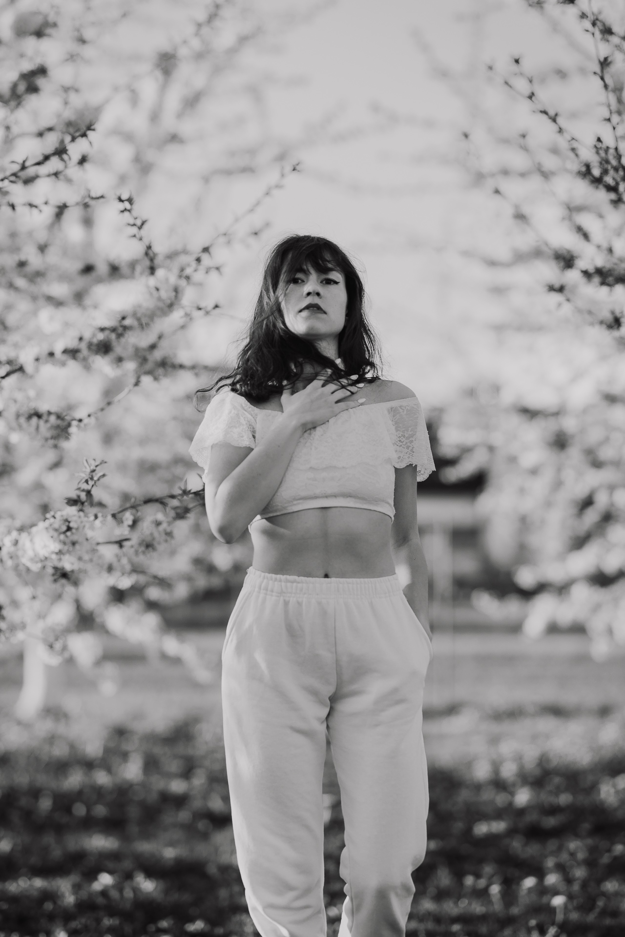 Kobieta w białym ubraniu na tle kwitnących drzew owocowych, sesja fotograficzna wiosenna w sadzie pod Krakowem