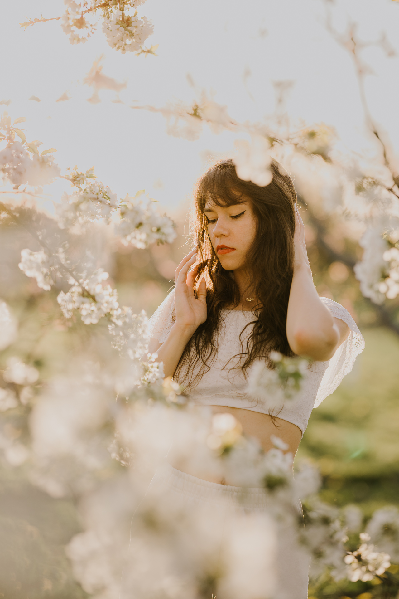 Kobieta w białym ubraniu na tle kwitnących drzew owocowych, sesja fotograficzna wiosenna w sadzie pod Krakowem
