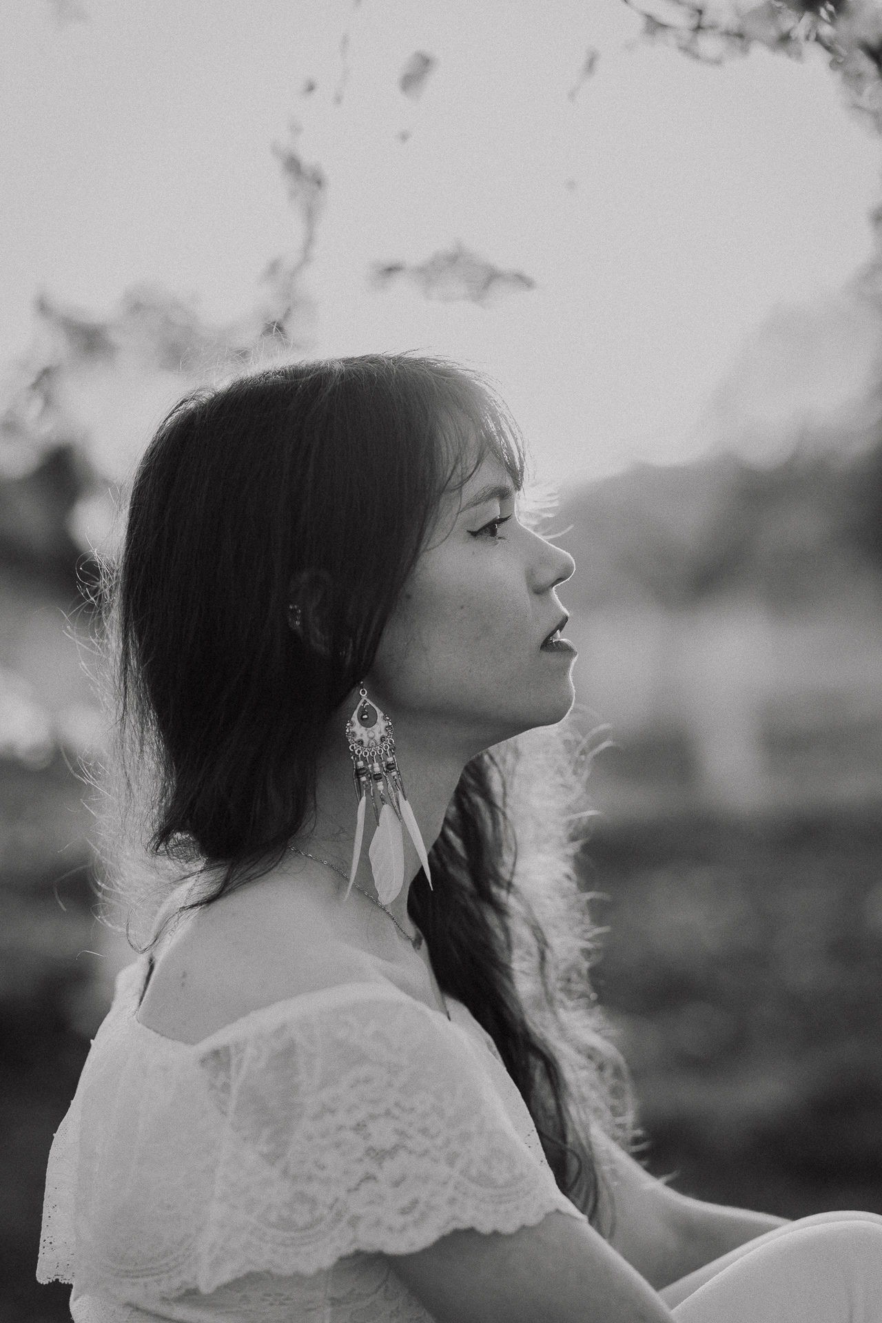 Portret kobiecy w kwitnącym sadzie podczas zachodzącego słońca pod Krakowem, modelka wśród jabłoni w pełnym rozkwicie, wiosenna sesja fotograficzna