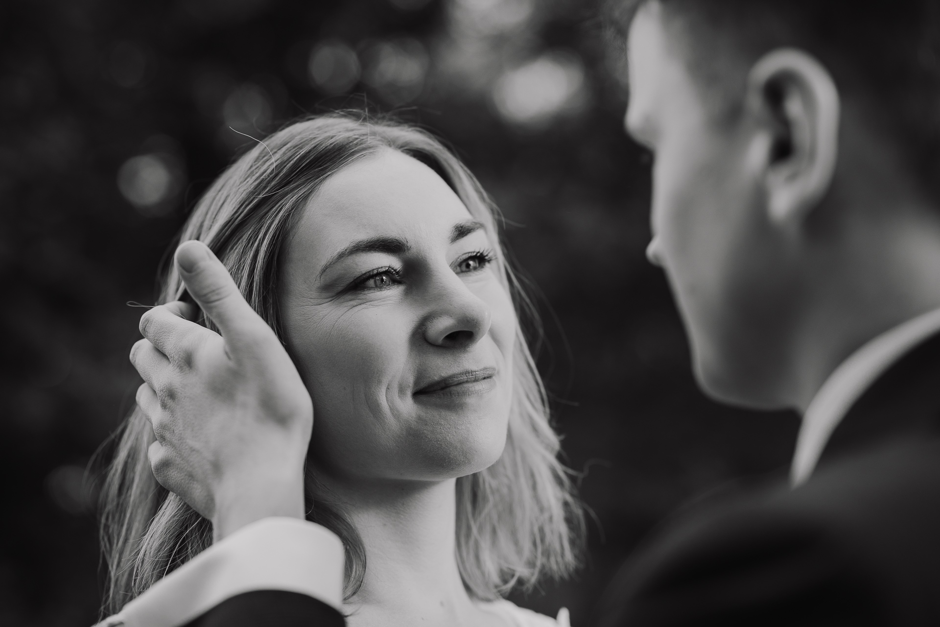 Pan Młody gładzi włosy Panny Młodej podczas sesji poślubnej