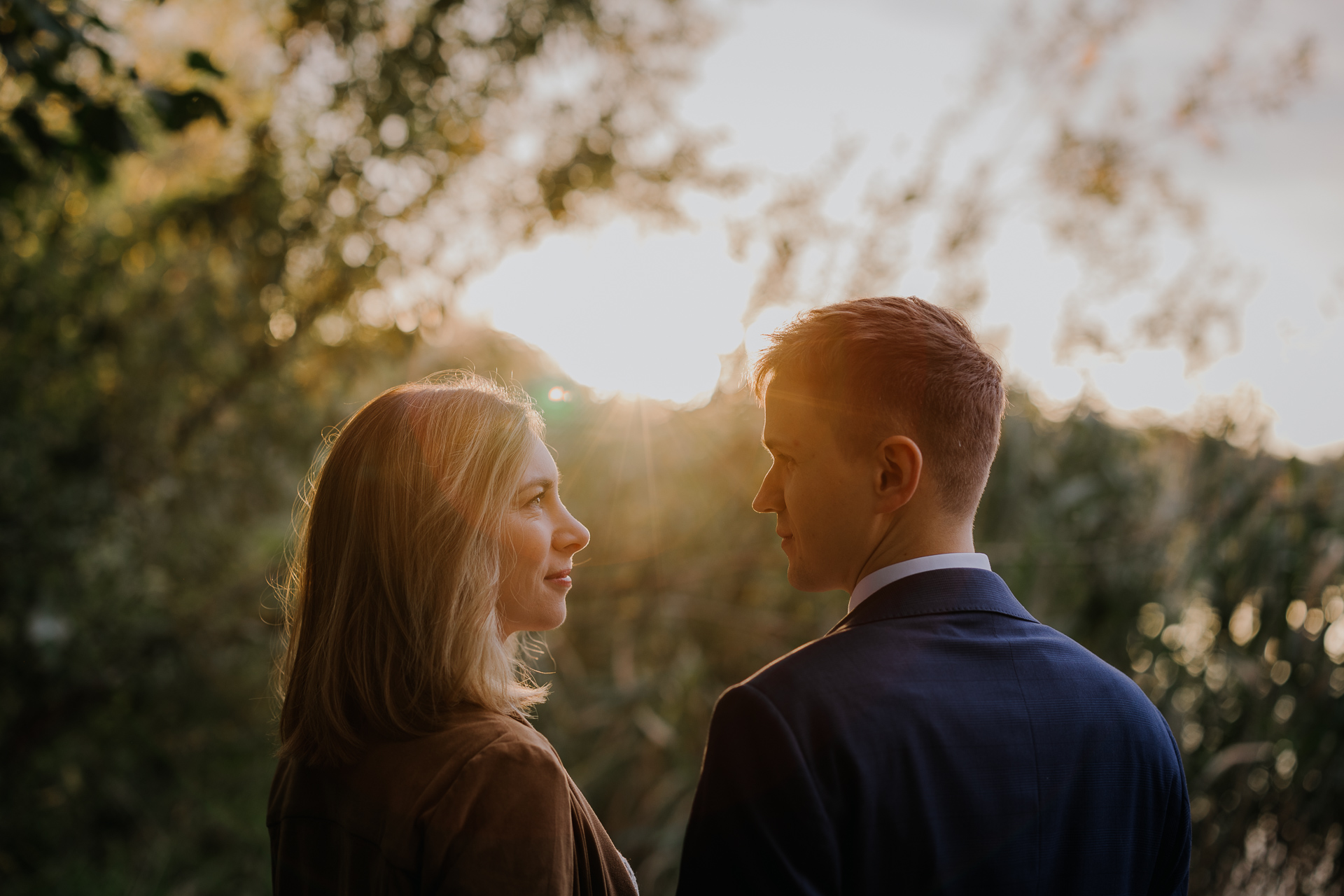 państwo młodzi patzą na siebie na tle zachodzącego słońca