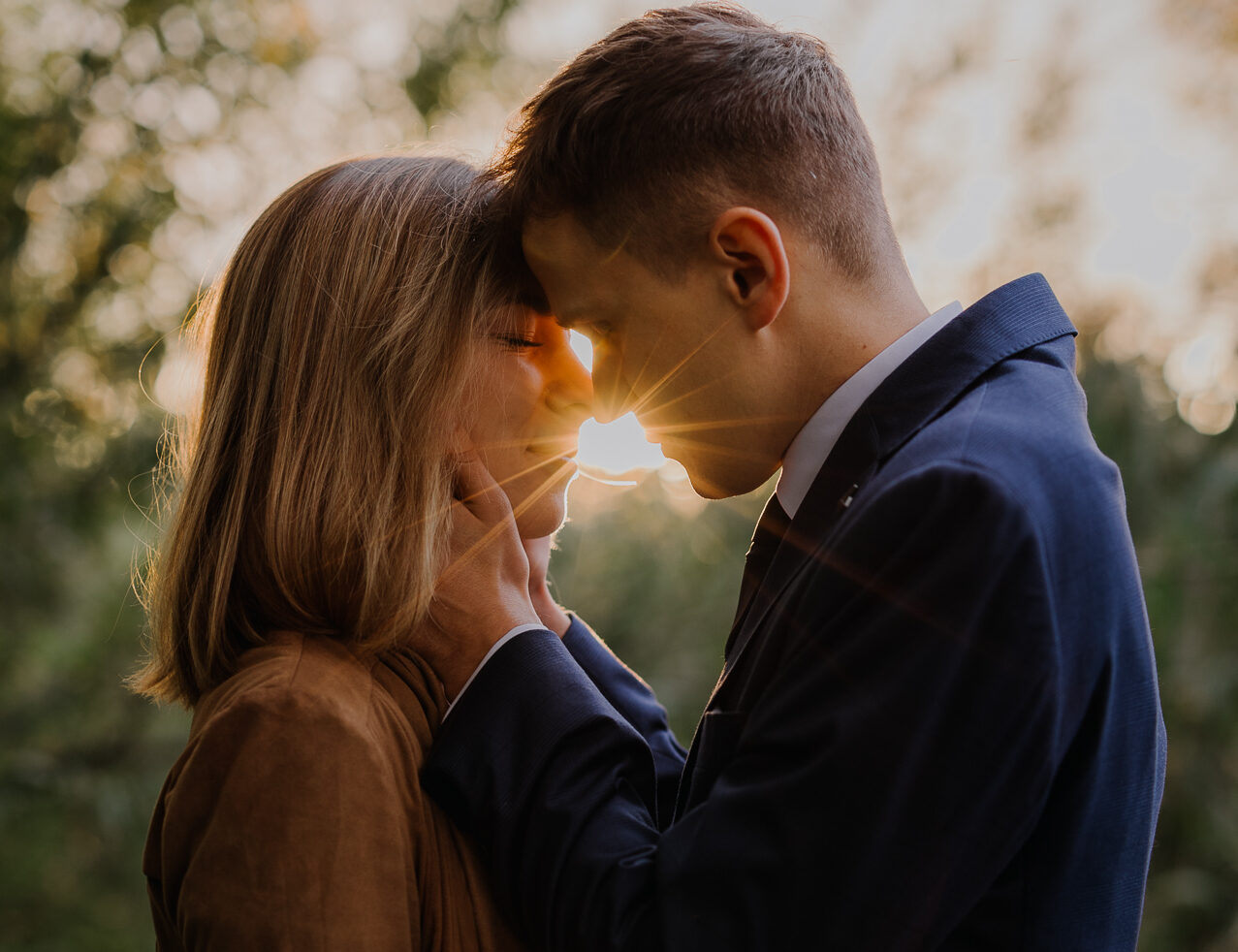 państwo młodzi przytulają się na tle zachodzącego słońca w Przylasku Rusieckim