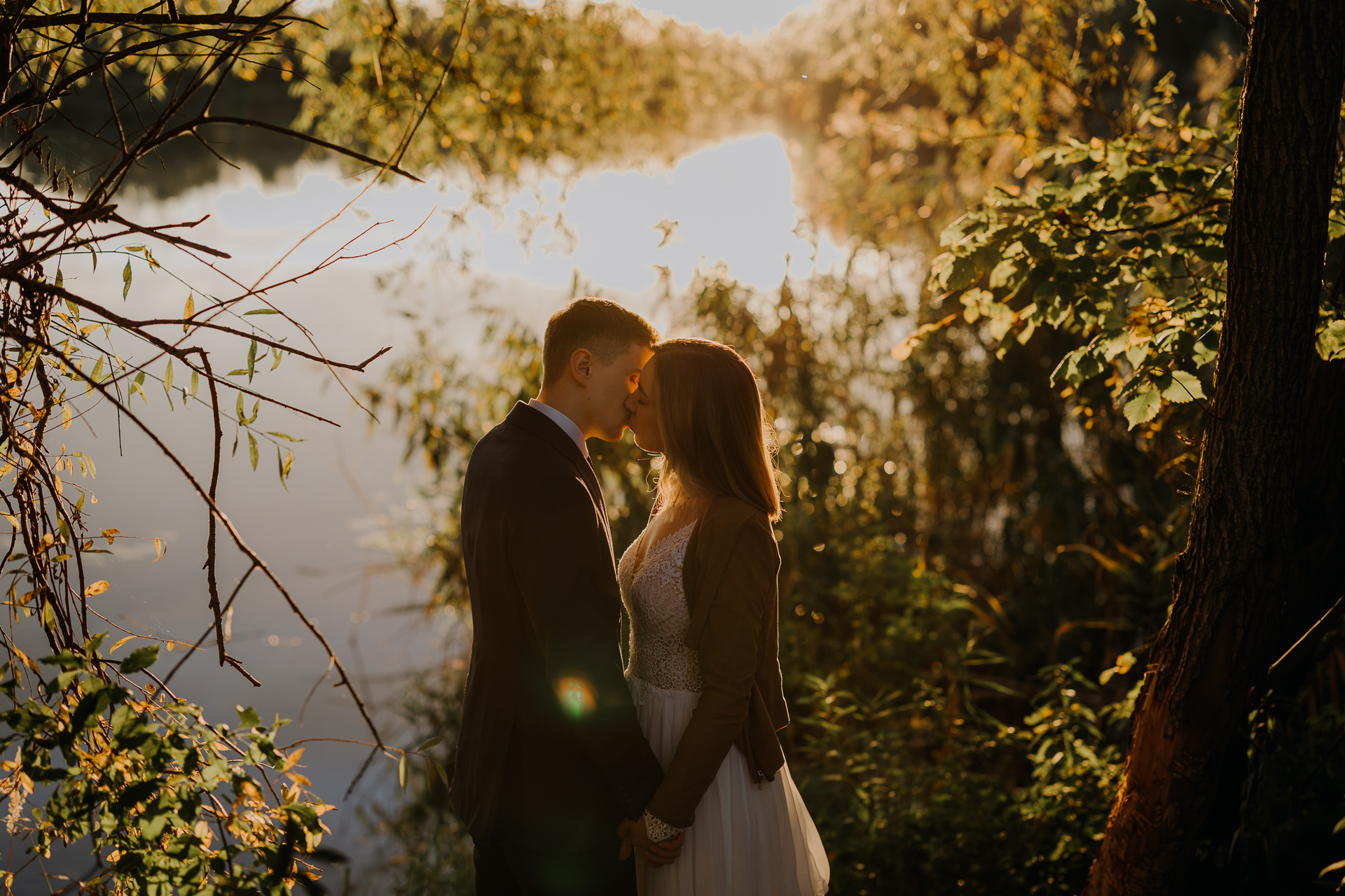 państwo młodzi przytulają się na tle zachodzącego słońca
