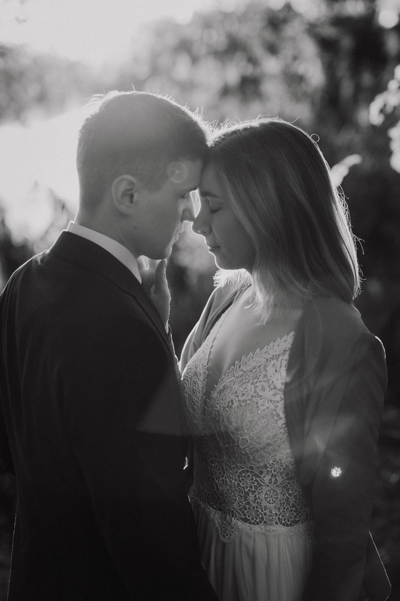 państwo młodzi przytulają się na tle zachodzącego słońca