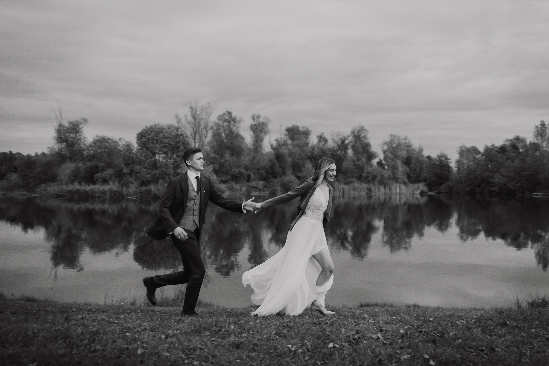 Para młoda biegnie na tle stawu w przylasku rusieckim