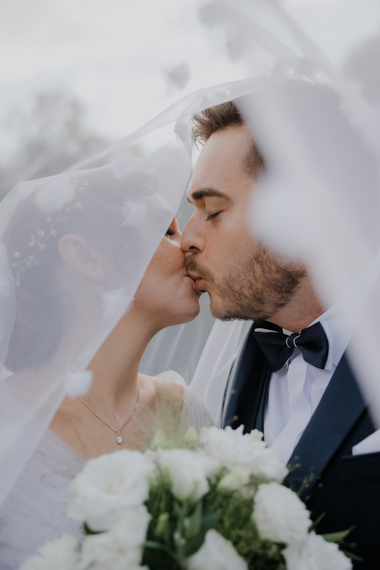 Nowożeńcy całują się pod welonem w arboretum Bolestraszyce, plenerowa sesja poślubna, profesjonalna fotografia ślubna