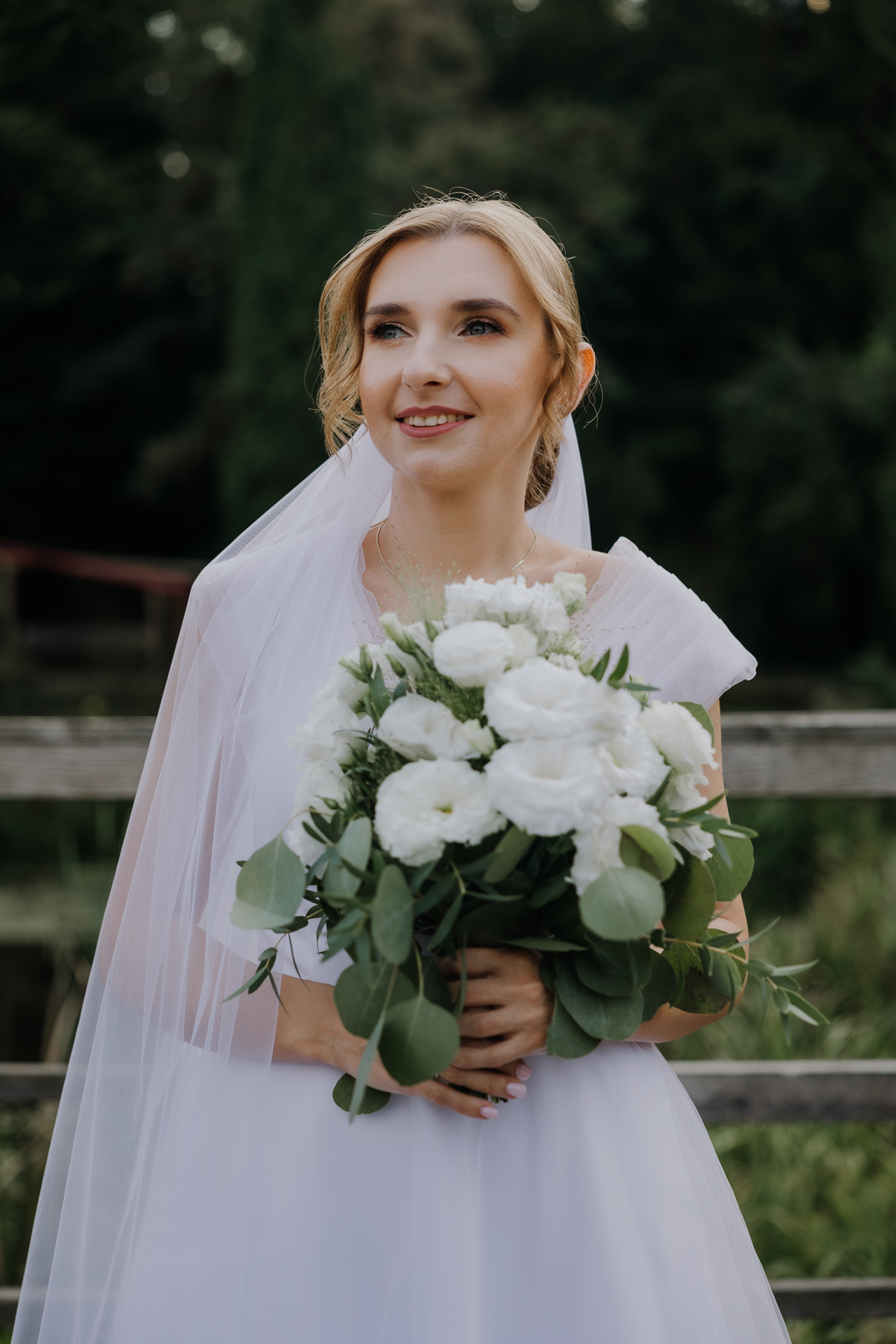 Portret panny młodej w białej sukni ślubnej pośród zieleni w Arboretum Bolestraszyce, romantyczna fotografia ślubna, okolice Przemyśla"