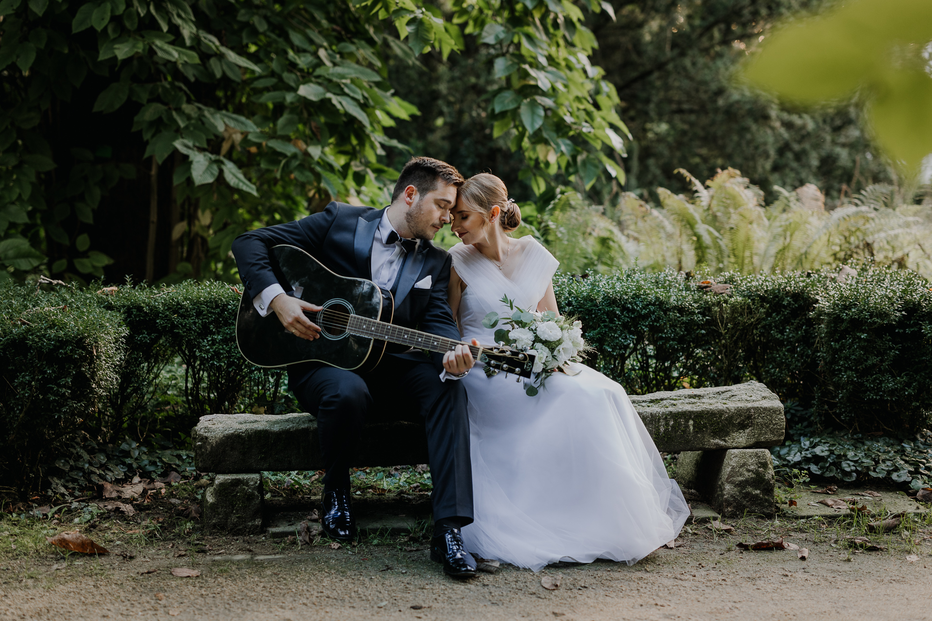 Pan Młody gra na gitarze Pannie Młodej podczas sesji poślubnej w arboretum Bolestraszyce, okolice Przemyśla