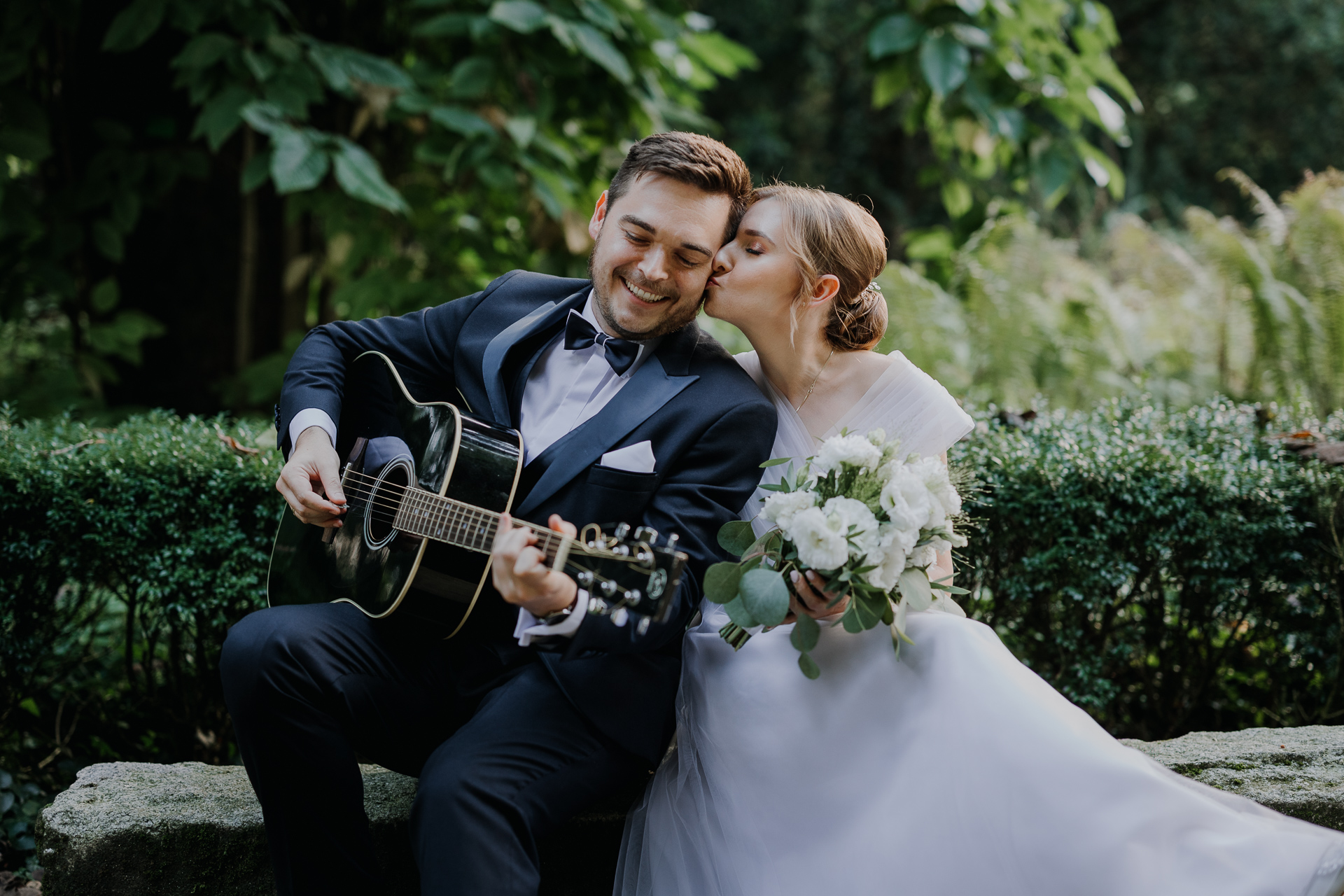 Pan Młody gra na gitarze Pannie Młodej podczas sesji poślubnej w arboretum Bolestraszyce, okolice Przemyśla