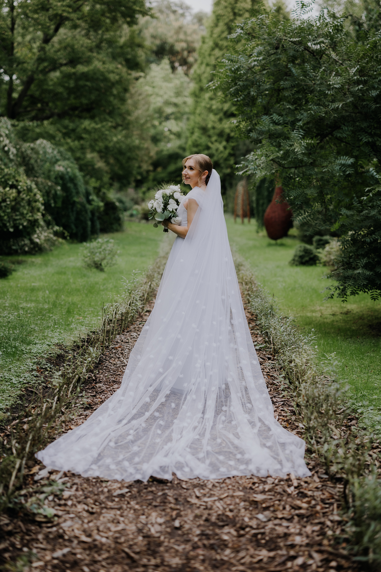 Portret panny młodej w białej sukni ślubnej pośród kwiatów arboretum Bolestraszyce, romantyczna fotografia ślubna, okolice Przemyśla