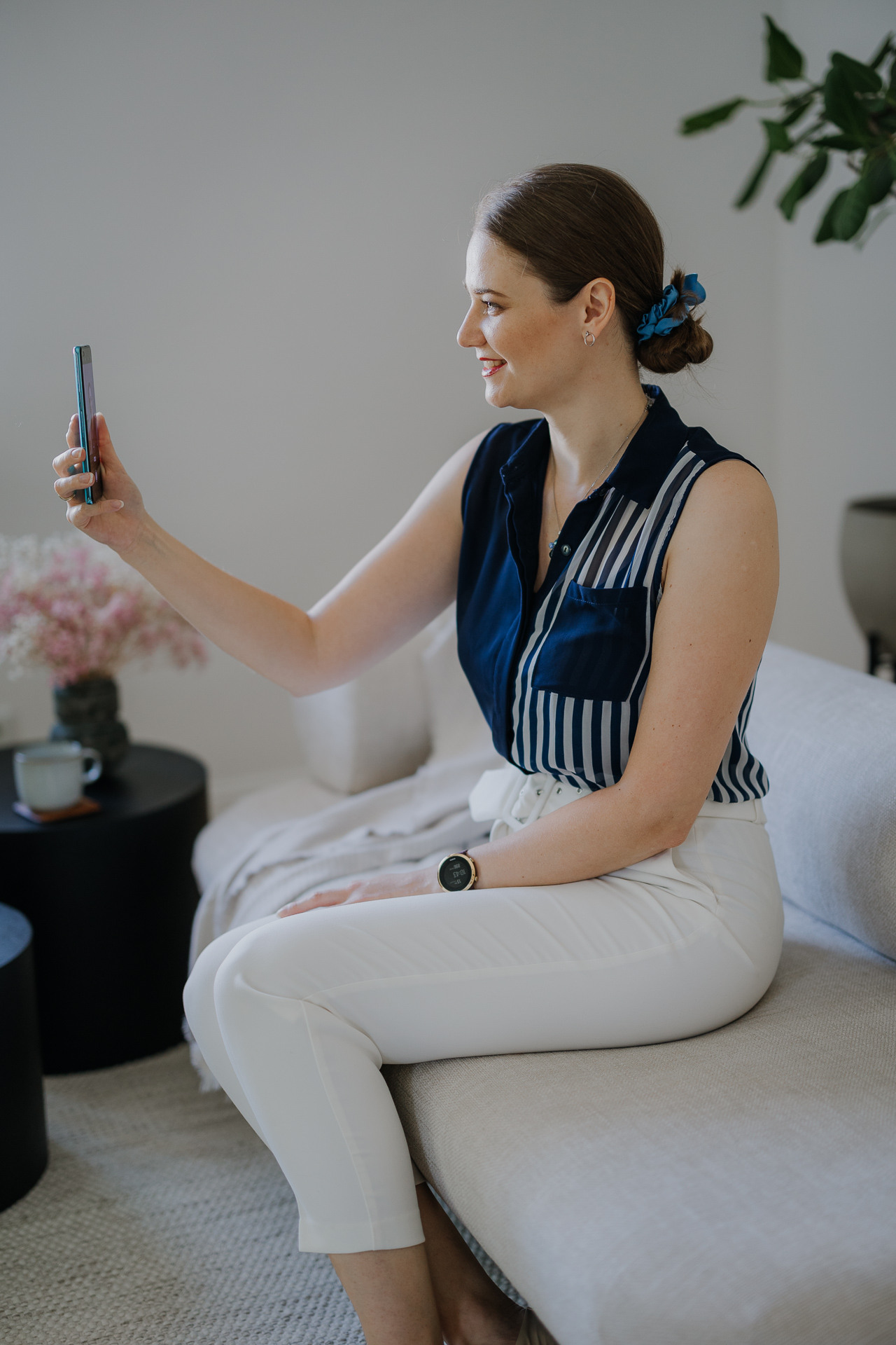 kobieta siedzi i uśmiecha się do telefonu podczas sesji wizerunkowej