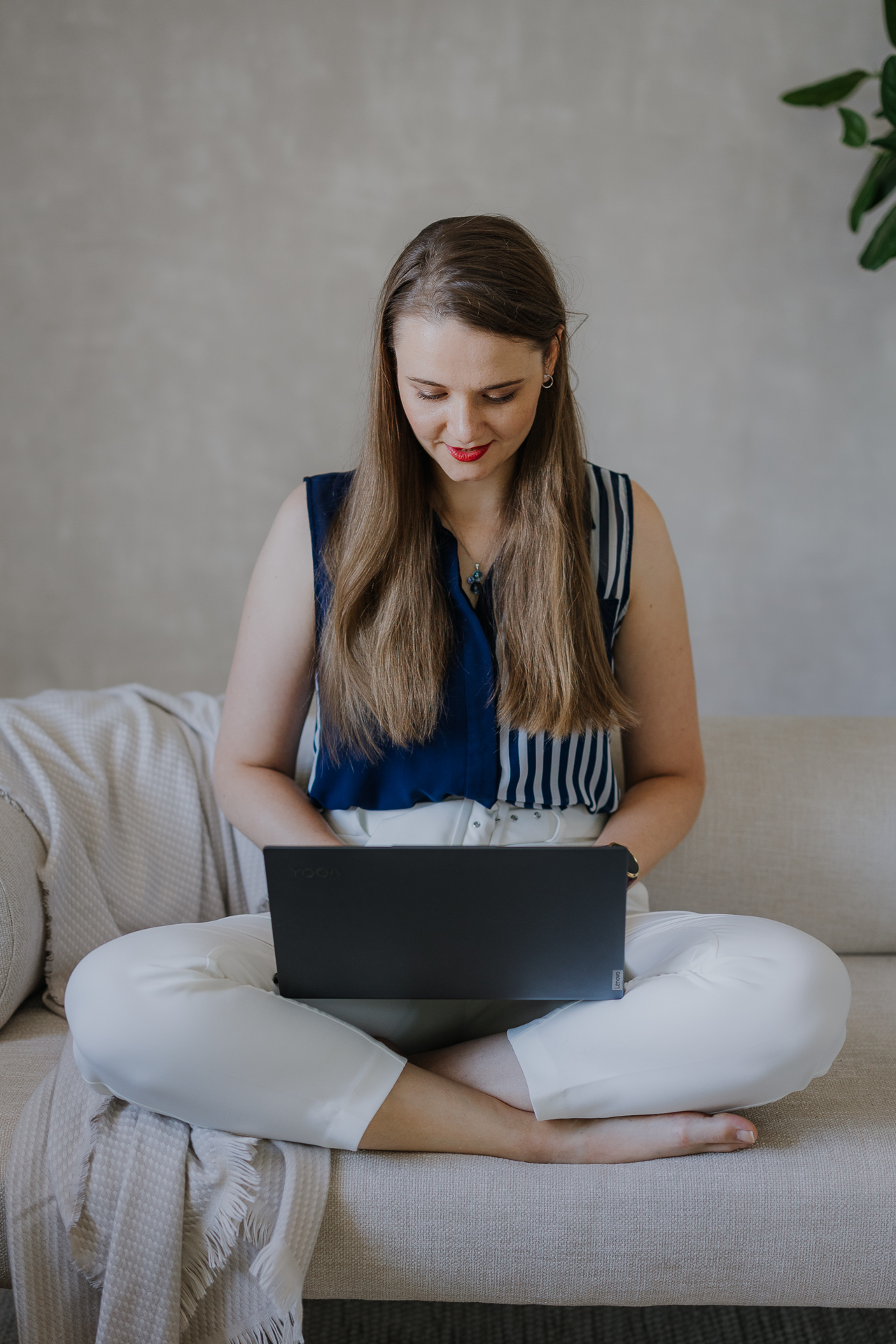 uśmiechnieta kobieta na sofie z laptopem podczas sesji wizerunkowej