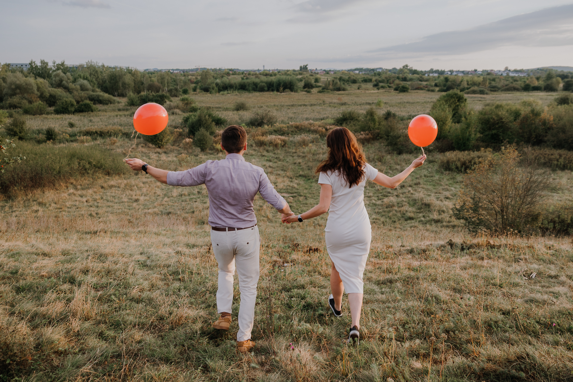 para narzeczonych biegnie z balonami na sesji zdjęciowej w Krakowie