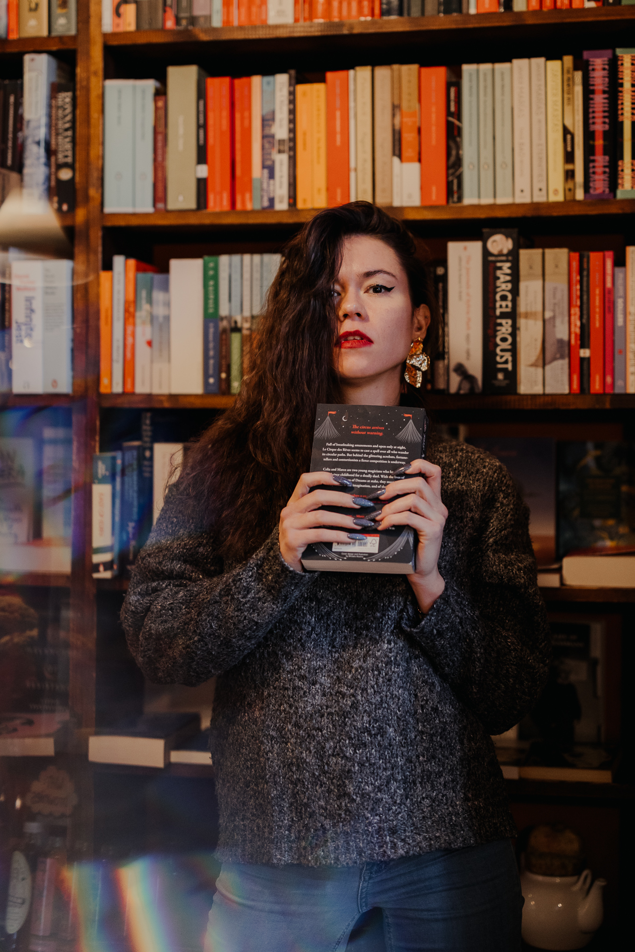 kobieta przy regale z książkami trzyma książkę w ręce