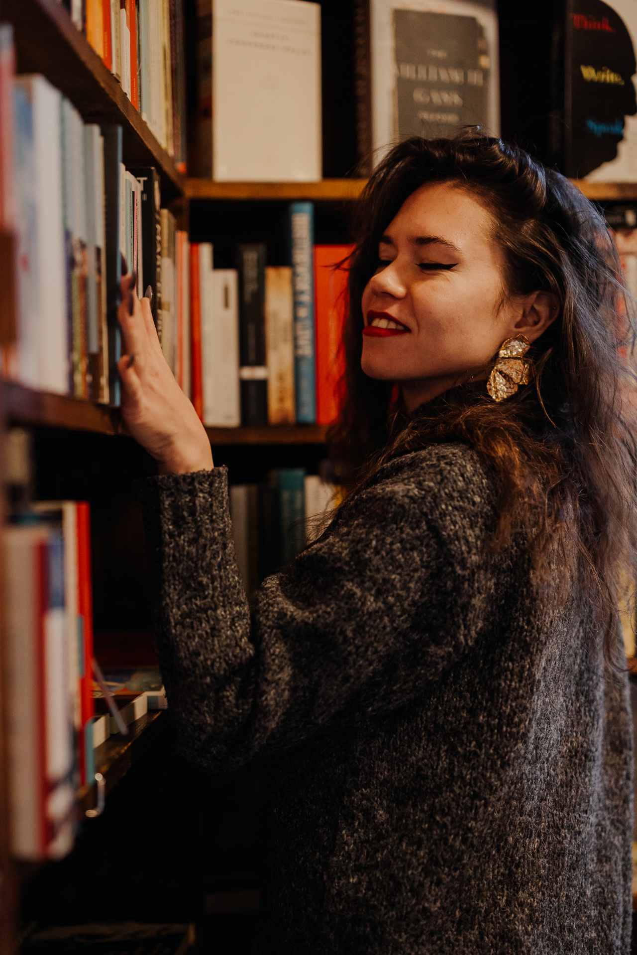 kobieta przesuwa ręką po regale z książkami