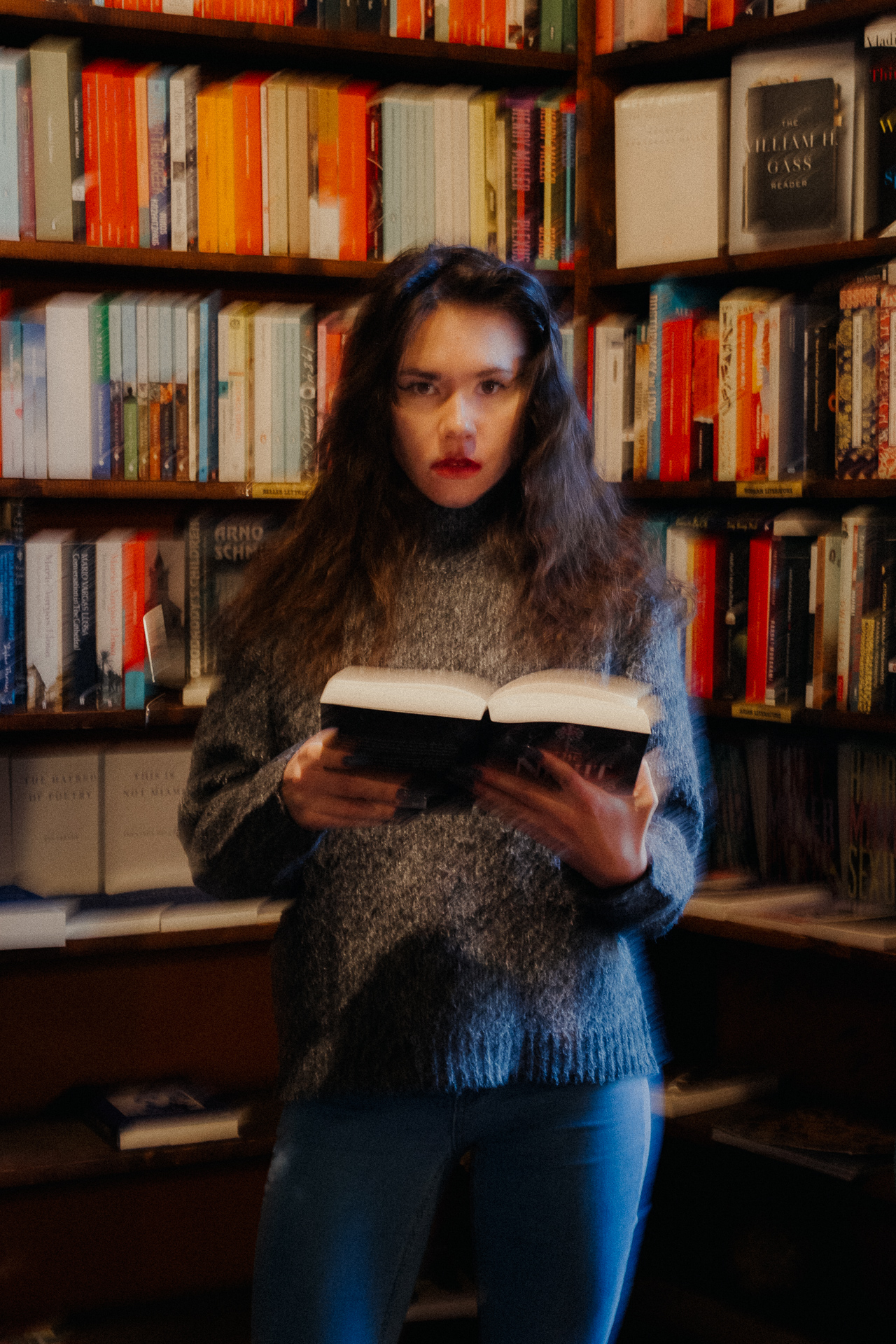 kobieta przy regale z książkami trzyma książkę w ręce