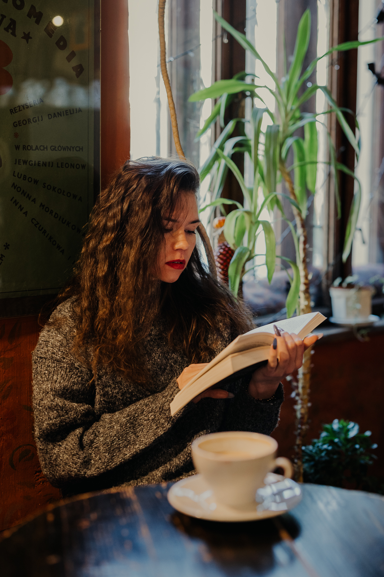 kobieta czyta książkę i pije kawę w kawiarni Massolit w Krakowie