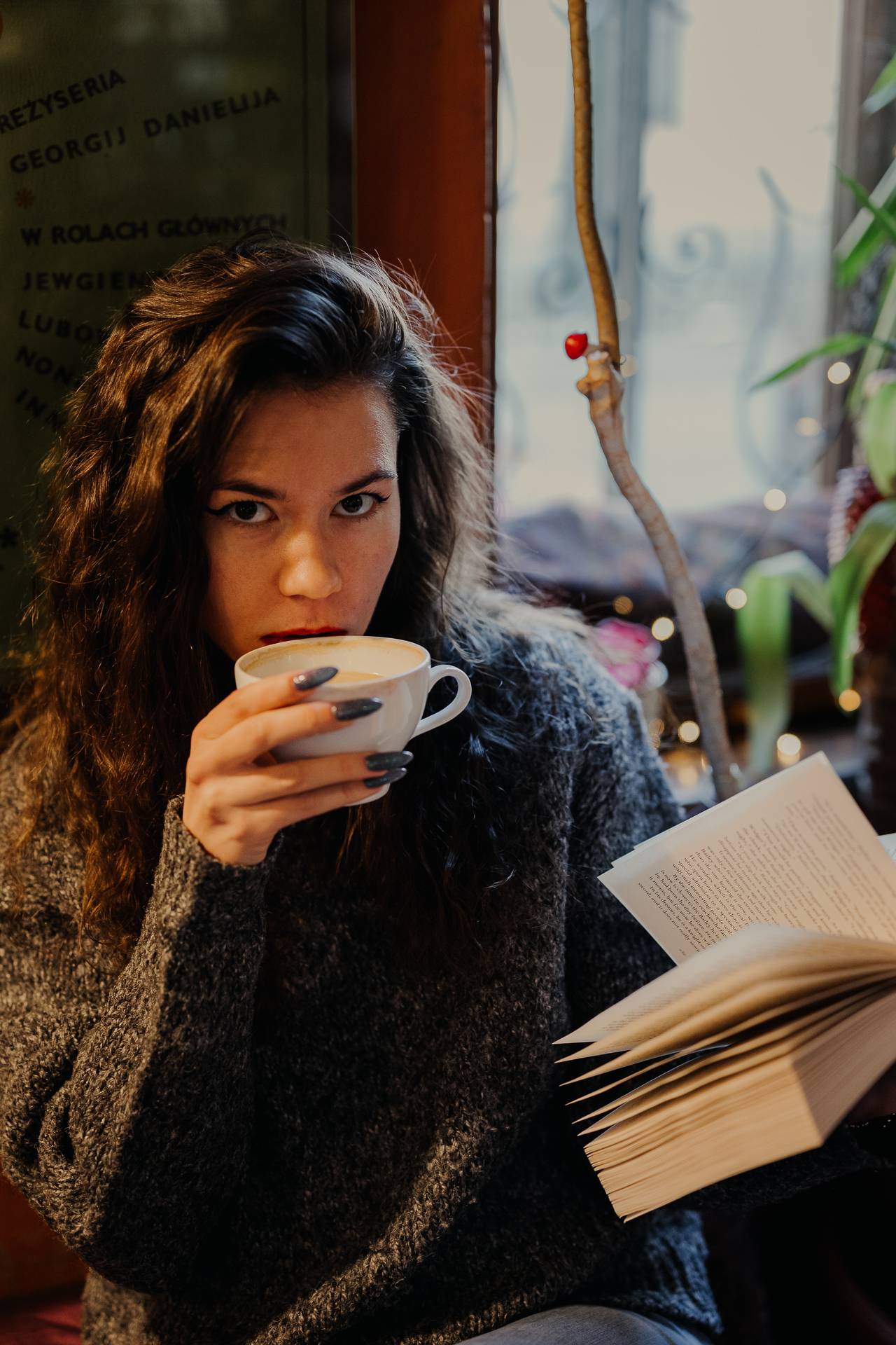kobieta czyta książkę i pije kawę w kawiarni Massolit w Krakowie