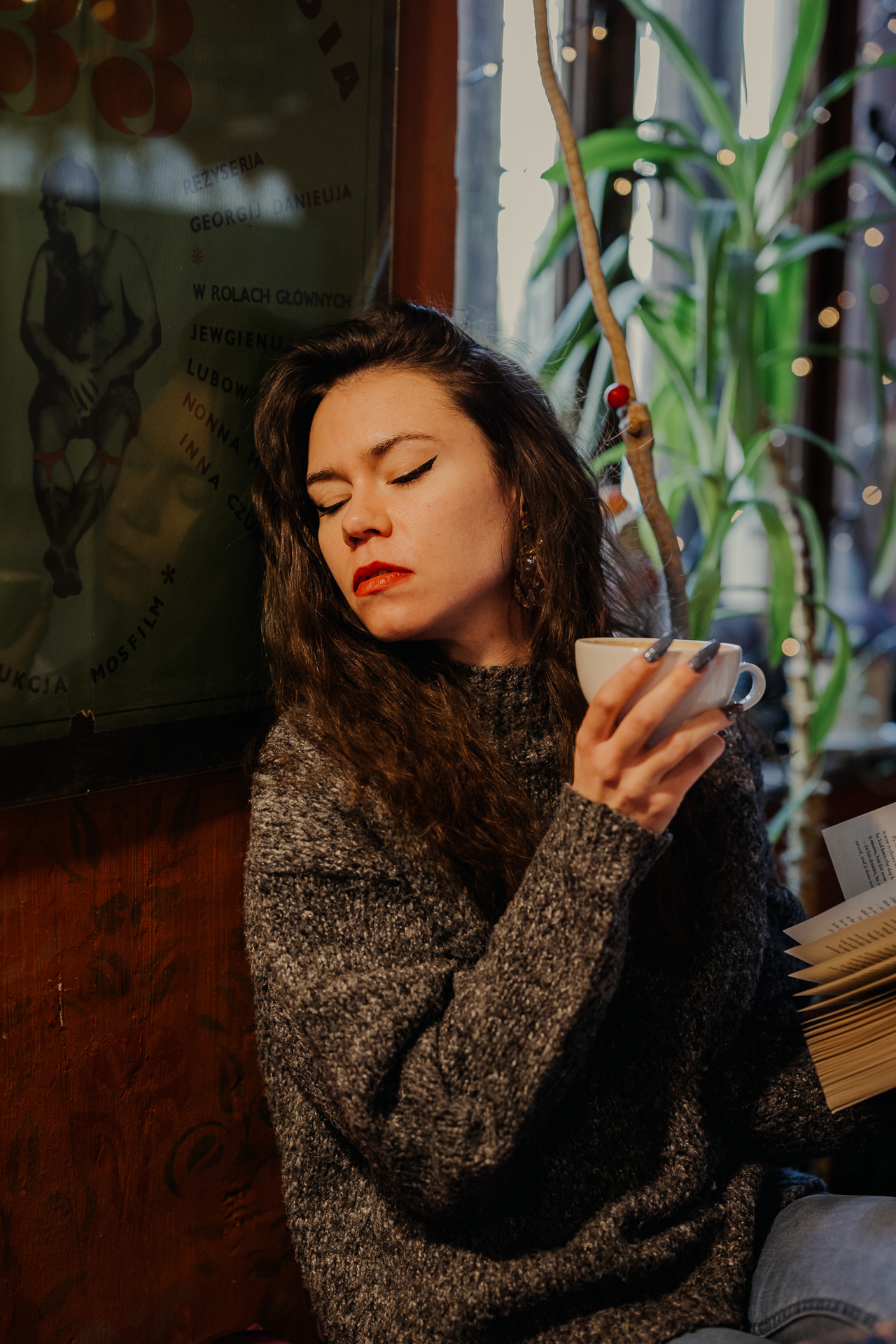 kobieta czyta książkę i pije kawę w kawiarni Massolit w Krakowie