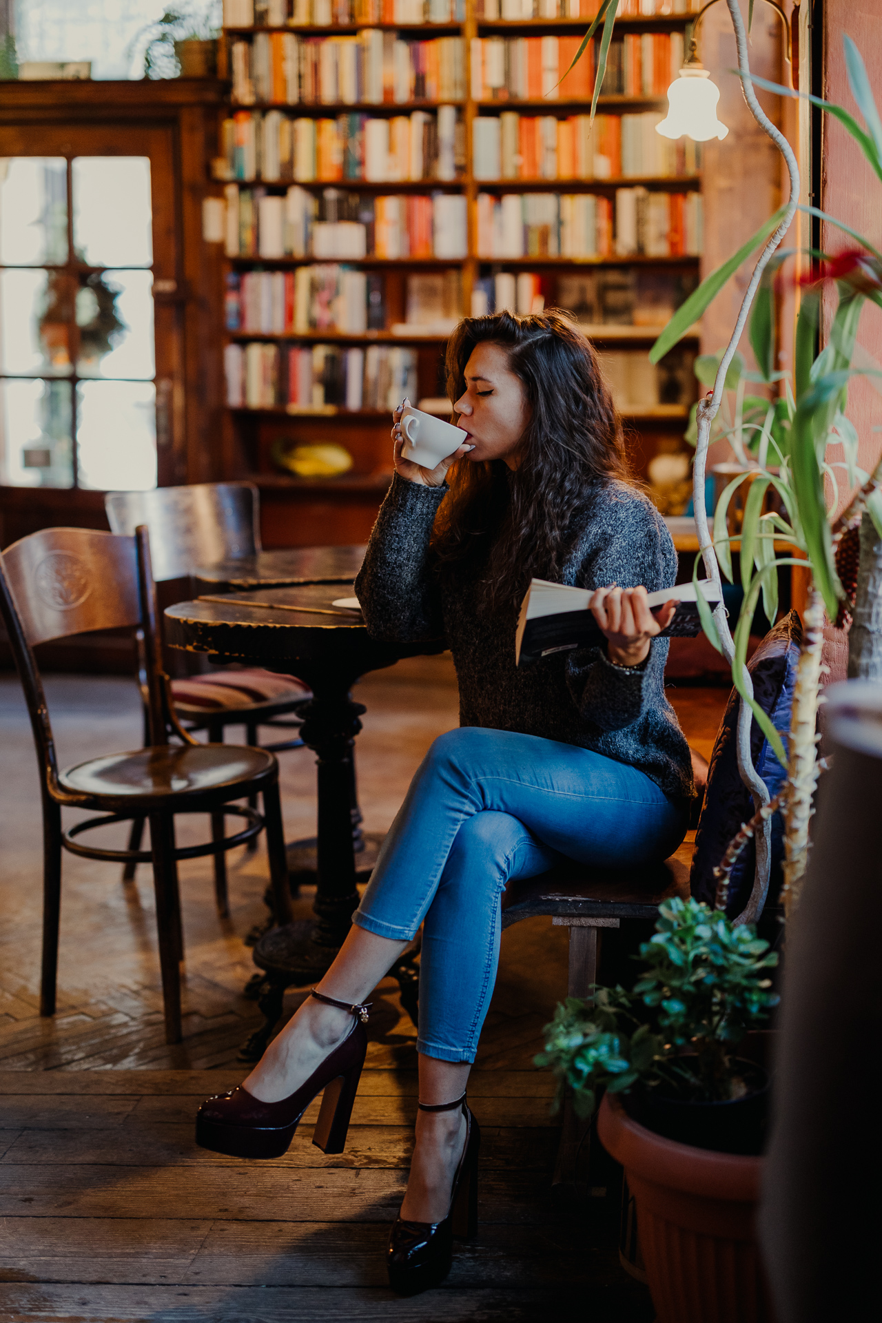 kobieta czyta książkę i pije kawę w kawiarni Massolit w Krakowie
