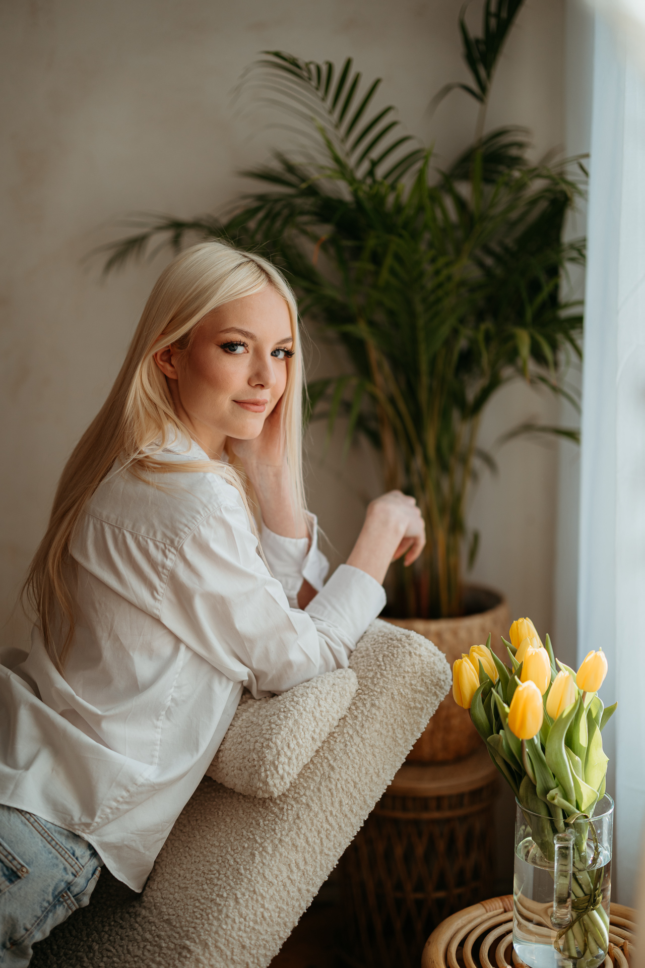 Kreatywne ujęcie kobiety leżącej na szezlongu, jej sylwetka w kontrze do światła, obok bukiet żółtych tulipanów, Atelier Basztowa