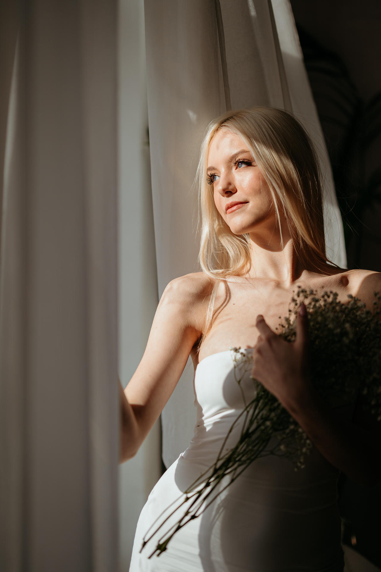 Kreatywne ujęcie kobiety stojącej przy oknie z bukietem gipsówki, Atelier Basztowa