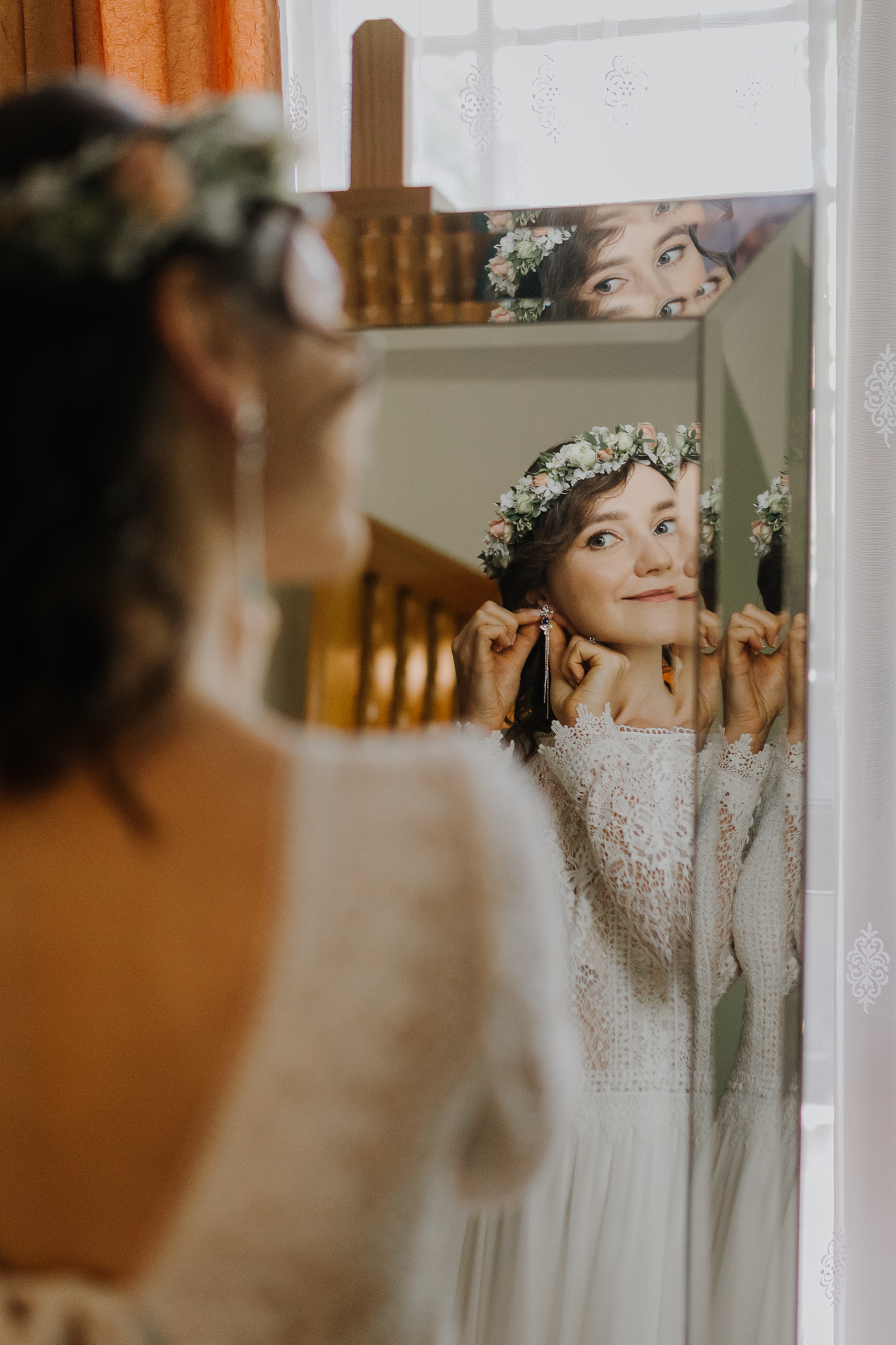 panna młoda ubiera kolczyki podczas przygotowań ślubnych