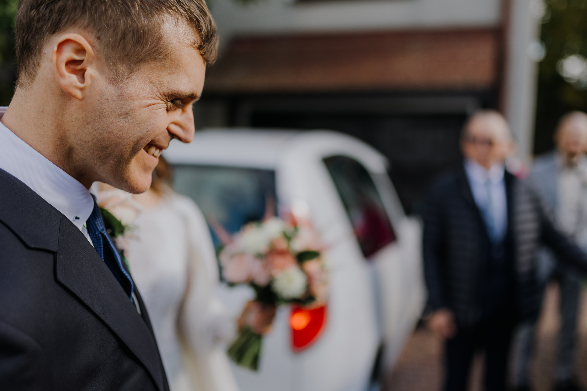 uśmiechnięty pan młody przy wsiadaniu do auta