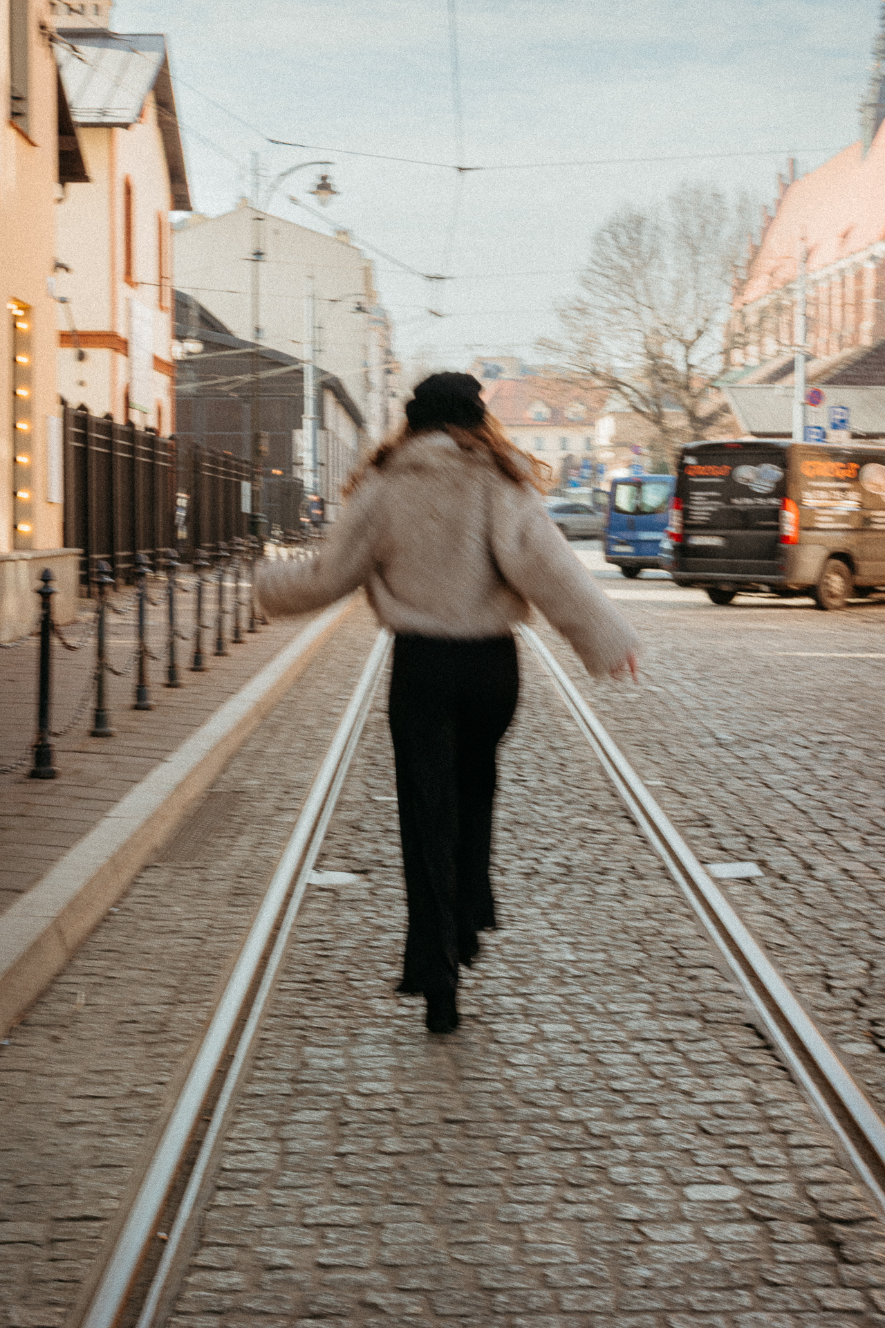 Sesja miejska_Wiktoria-40 Modelka w stylu francuskim biegnie po ulicy na krakowskim Kazimierzu, beret i futerko w paryskim stylu kontrastują z historyczną zabudową żydowskiej dzielnicy