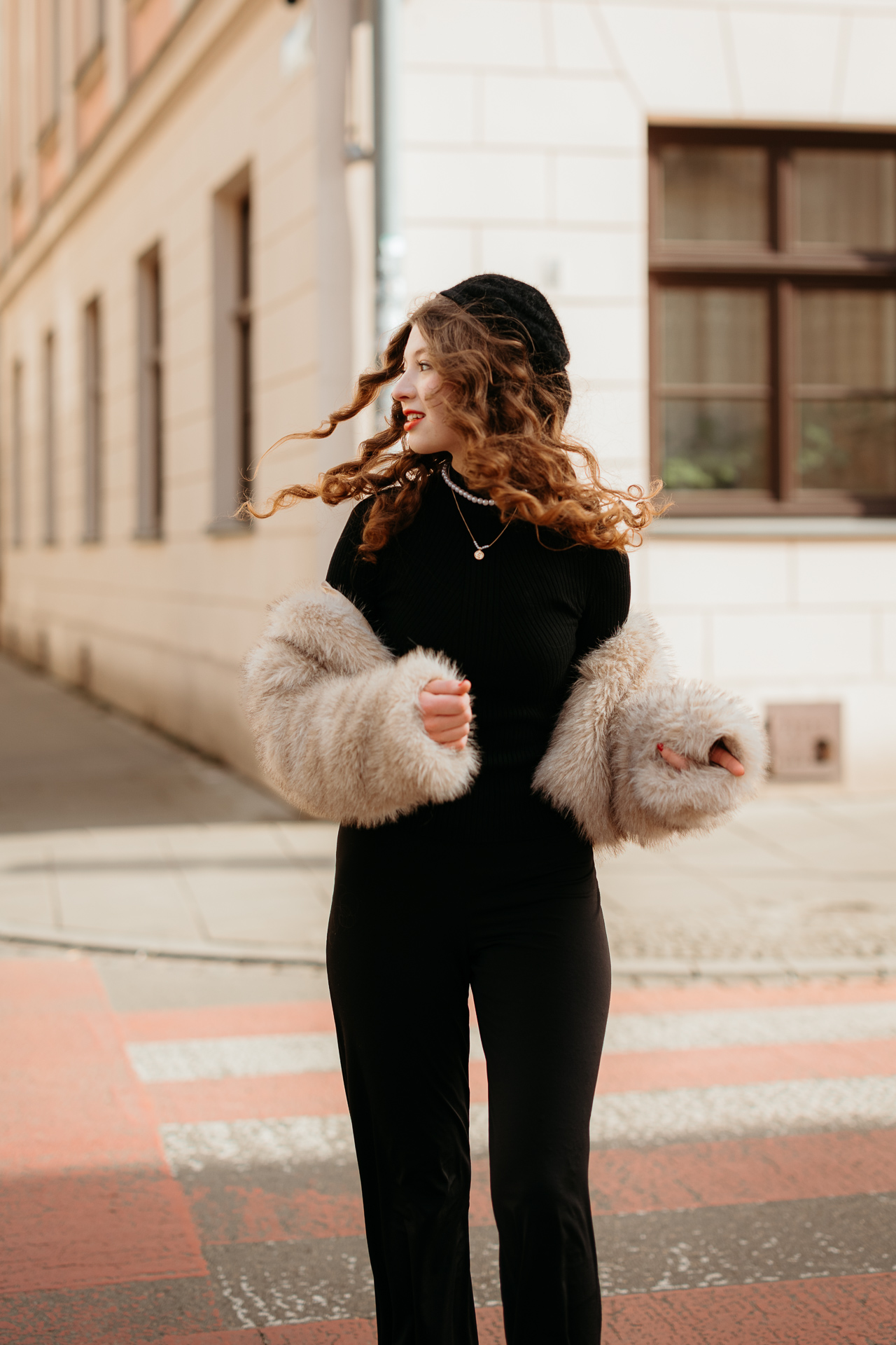 Sesja miejska_Wiktoria-56 Dynamiczne ujęcie modelki biegnącej przez przejście dla pieszych na Kazimierzu, jej francuska stylizacja z beretem i futerkiem ożywia zabytkową dzielnicę Krakowa