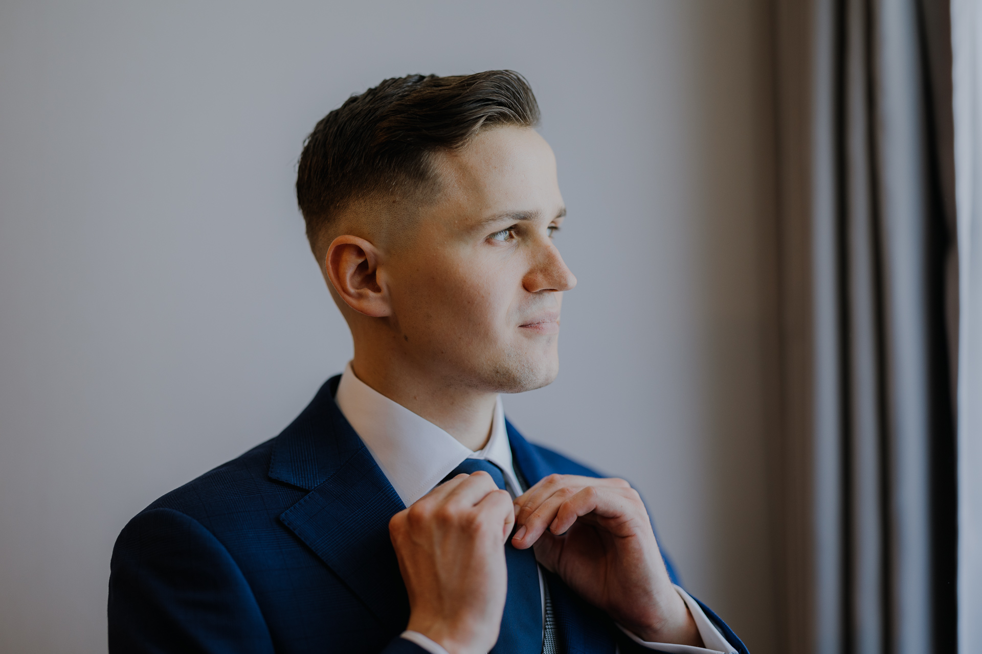 Pan młody poprawia krawat w trakcie przygotowań ślubnych