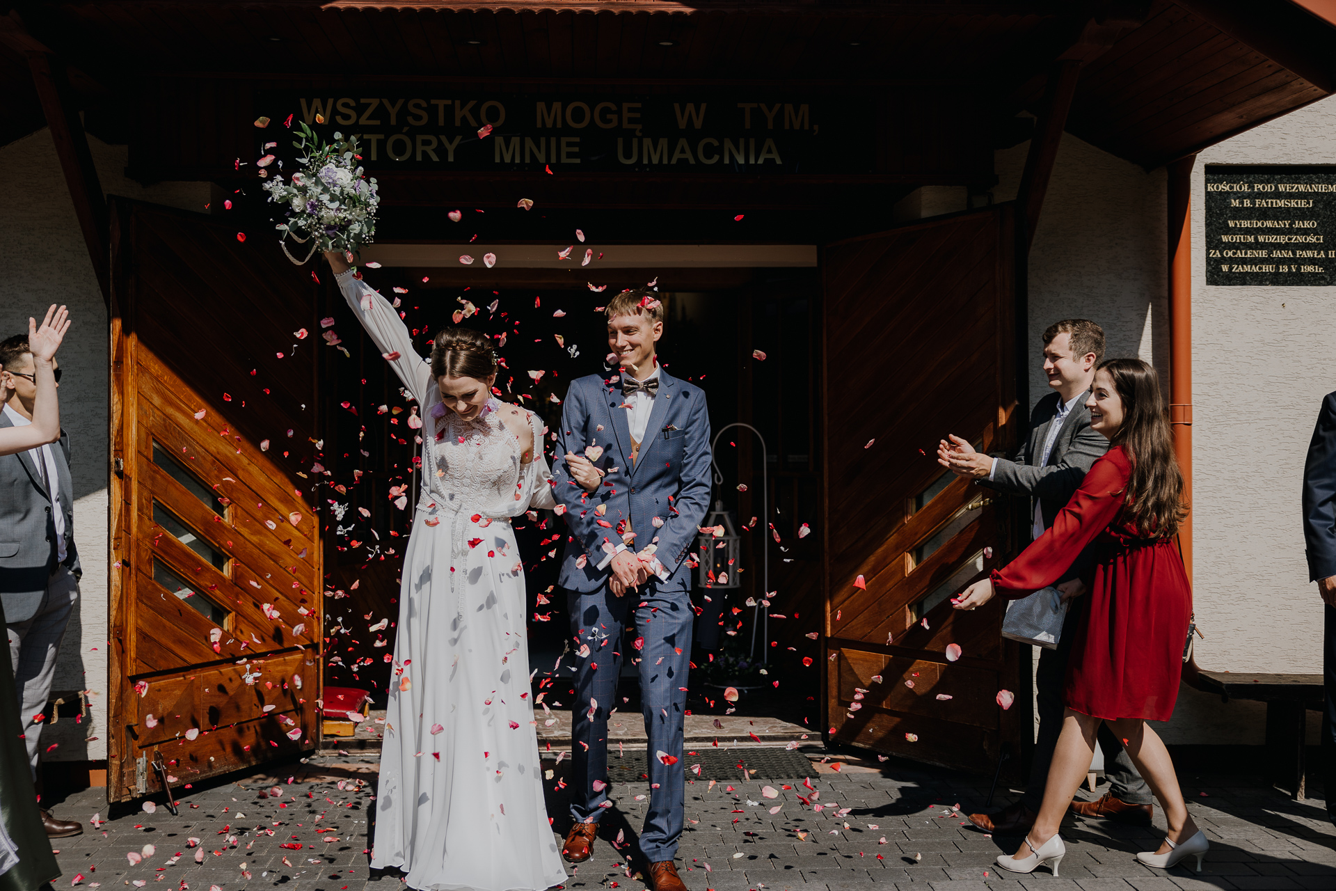 Państwo Młodzi obsypani kwiatami pod kościołem