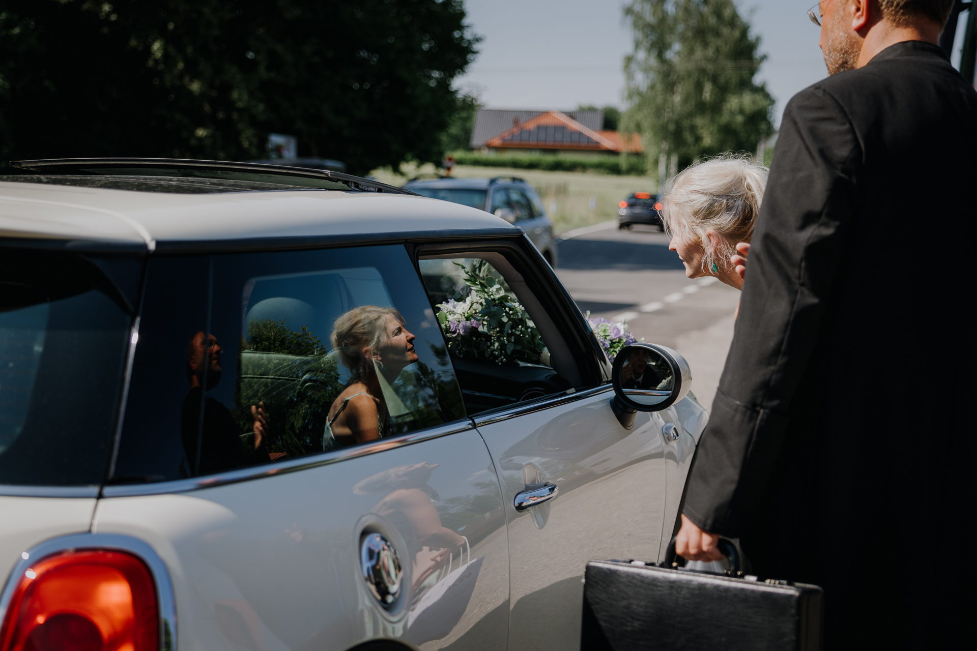 Siostra Panny Młodej rozmawia z nią przez otwartą szybę auta