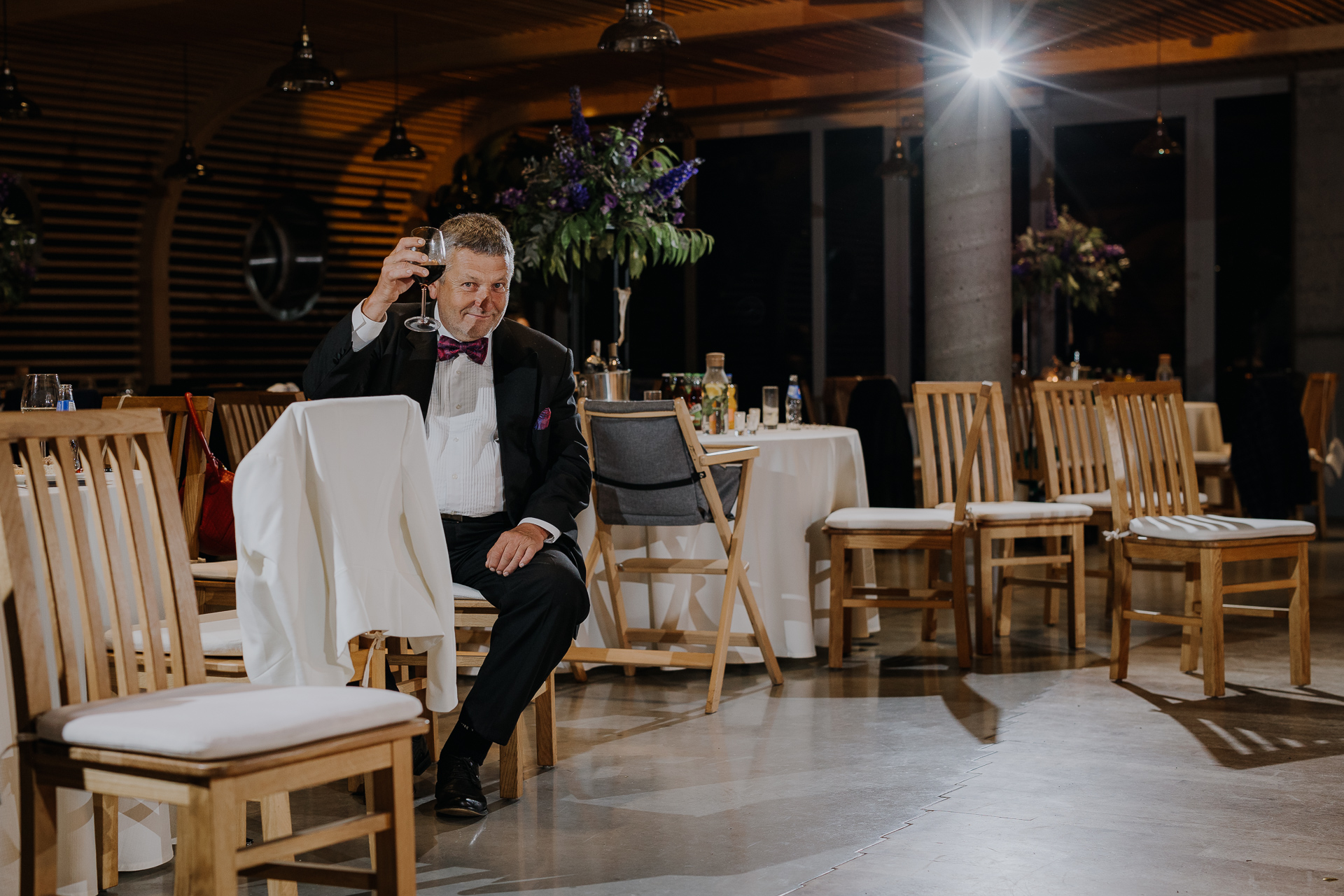 Gość weselny pokazuje wino po oczepinach