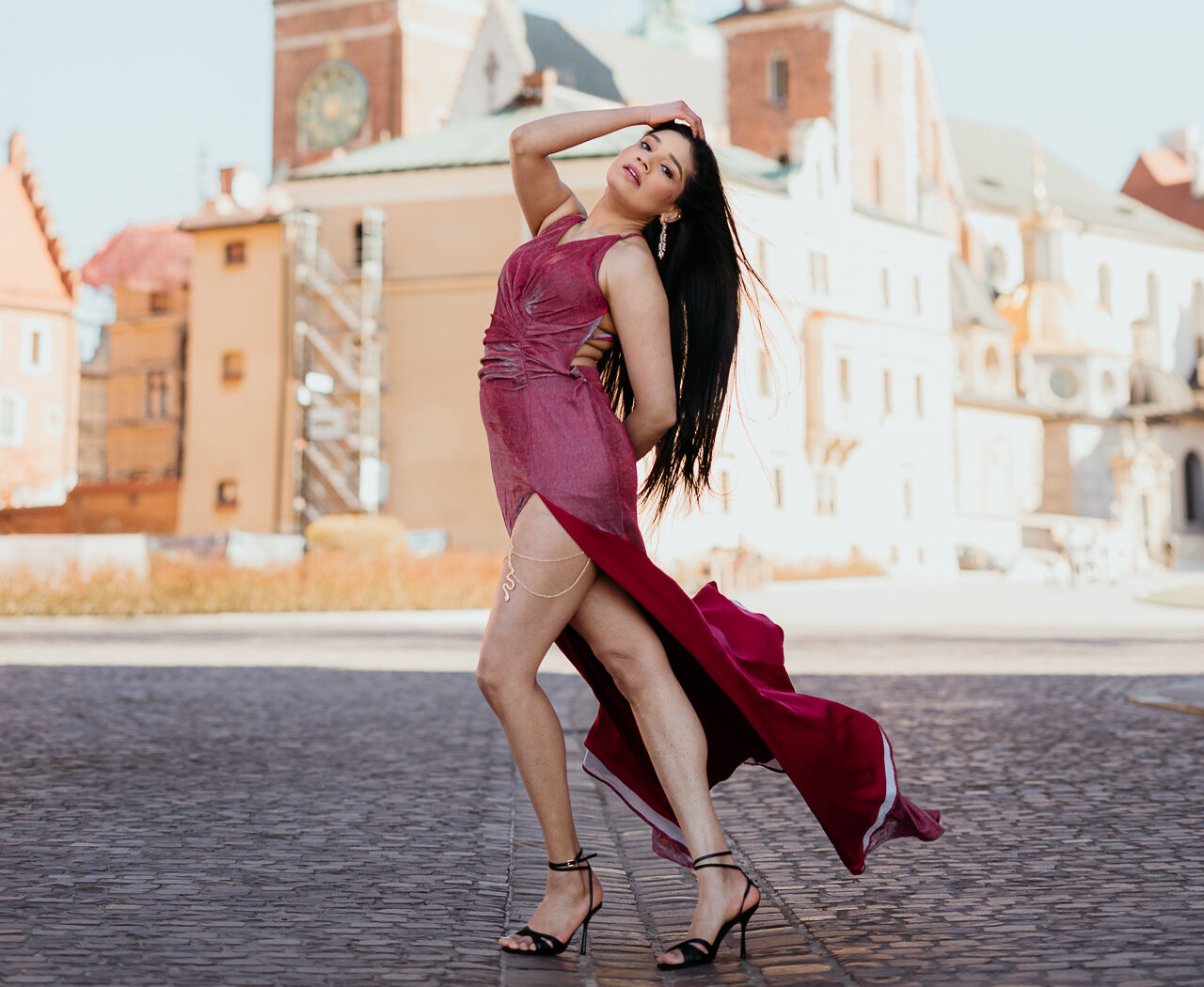 Modelka w wiśniowej sukni pozuje na tle Wawelu