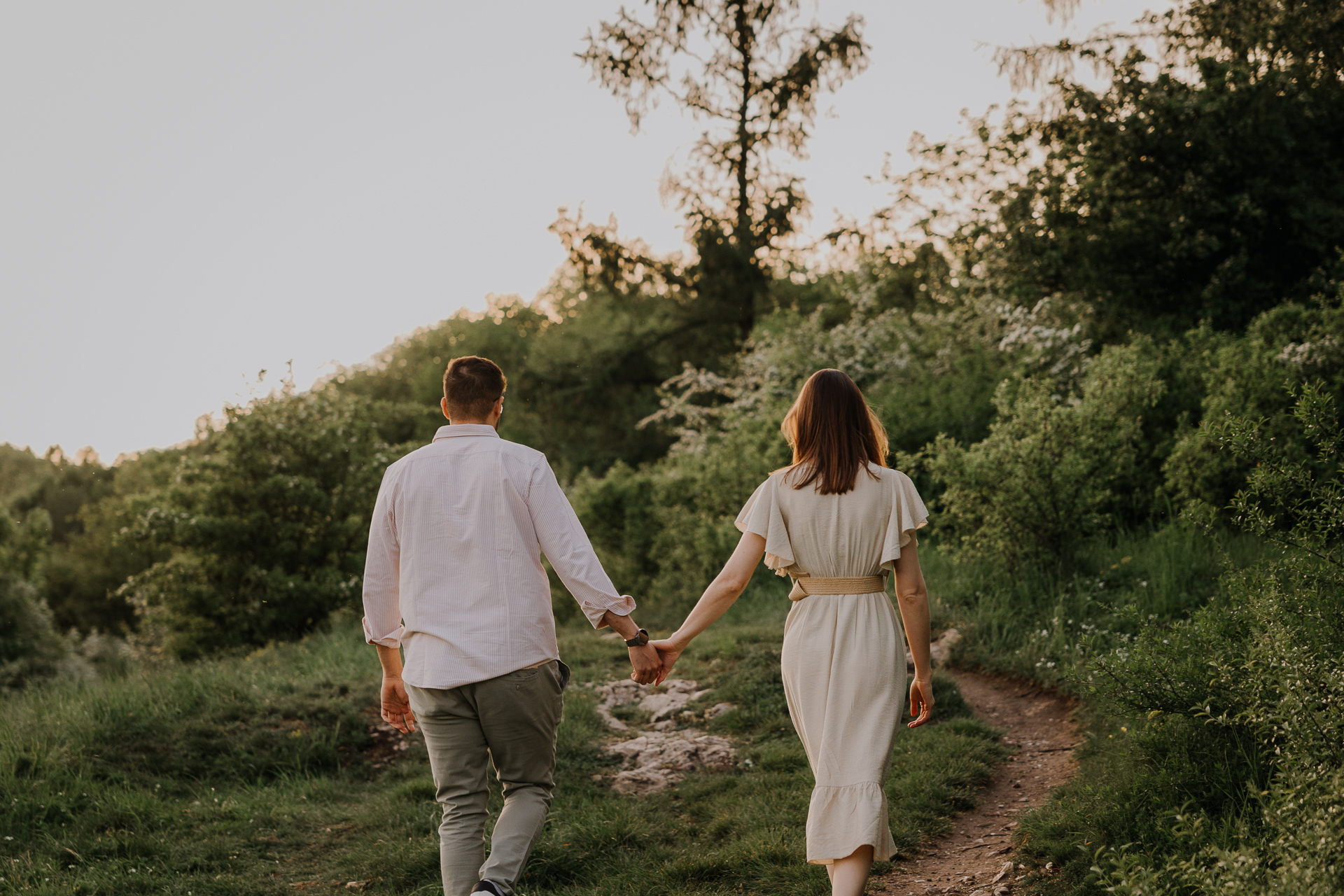 Para narzeczonych idzie w stronę słońca podczas sesji narzeczeńskiej