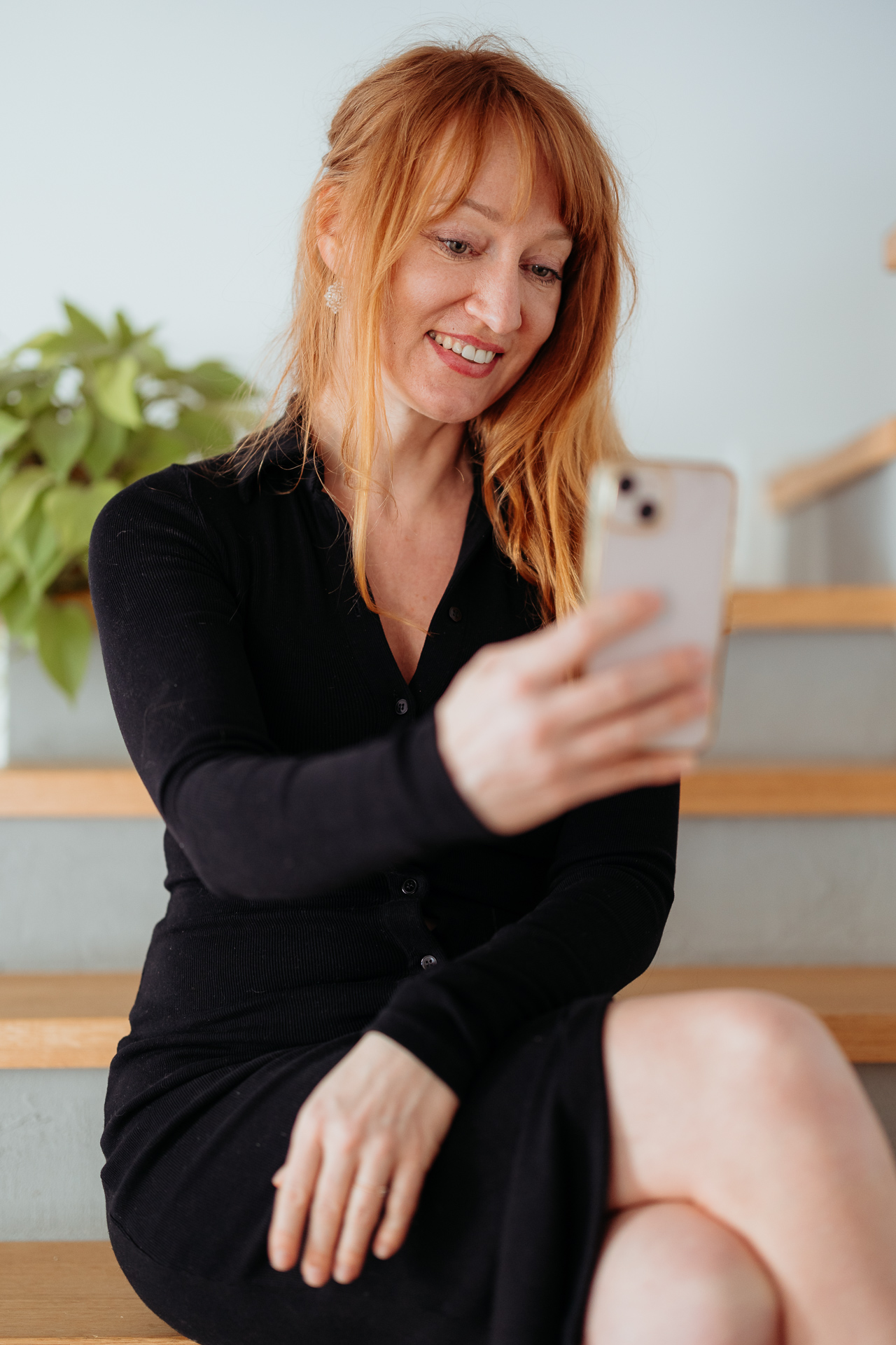 kobieta siedzi i uśmiecha się do telefonu podczas sesji wizerunkowej