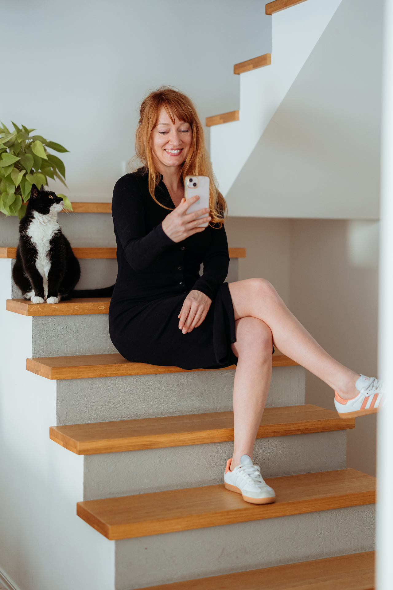 kobieta siedzi i uśmiecha się do telefonu podczas sesji wizerunkowej