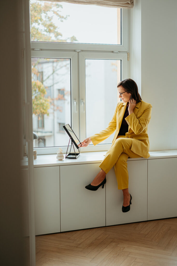 profesjonalna sesja wizerunkowa w studio dla marki osobistej, kobieta w kanarkowym garniturze uśmiecha się do siebie w lustrze