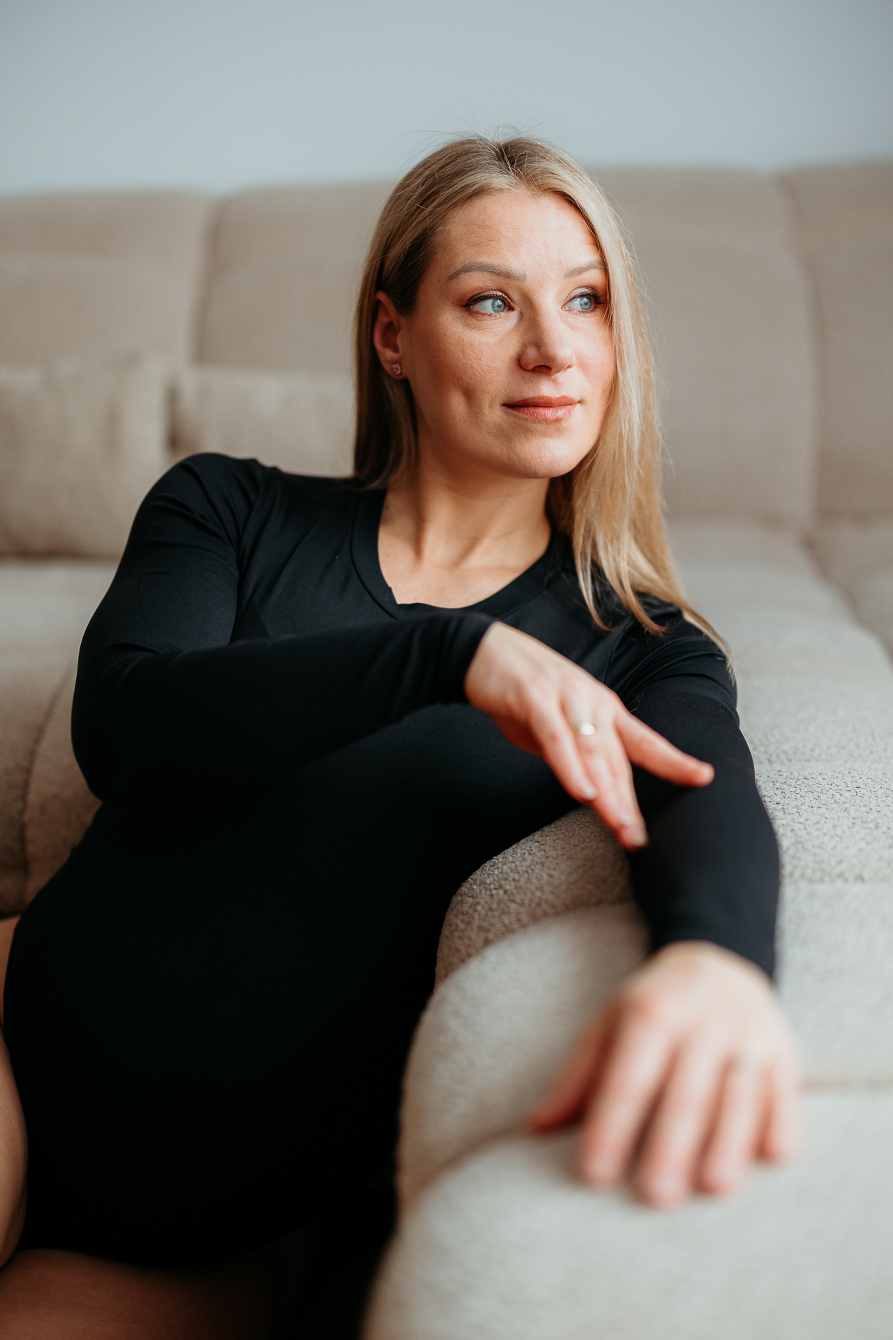 Kobieta w ciąży siedzi oparta o sofę u siebie w domu, Kraków