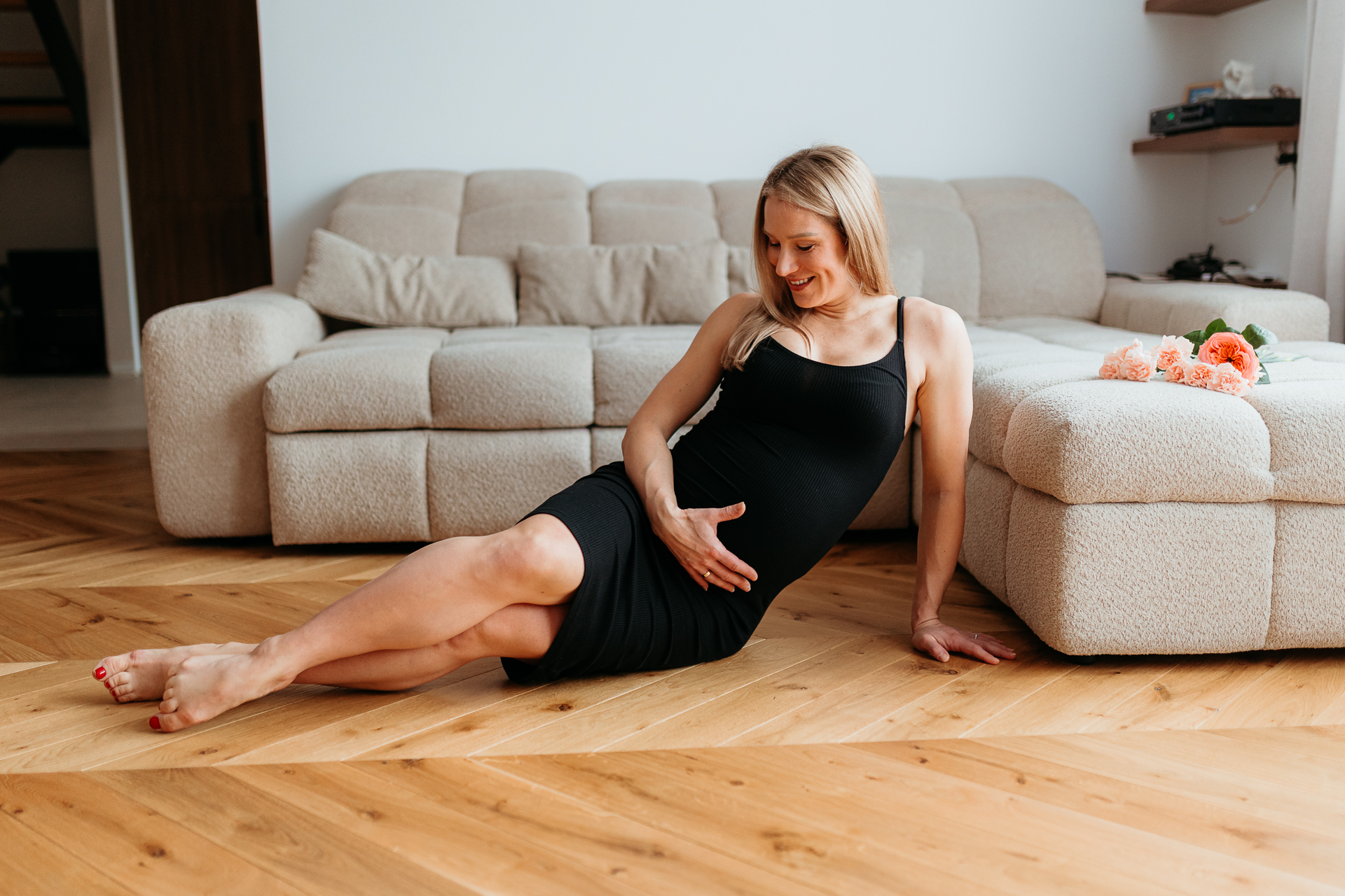 Uśmiechnięta kobieta w ciąży siedzi na podłodze u siebie w domu, Kraków