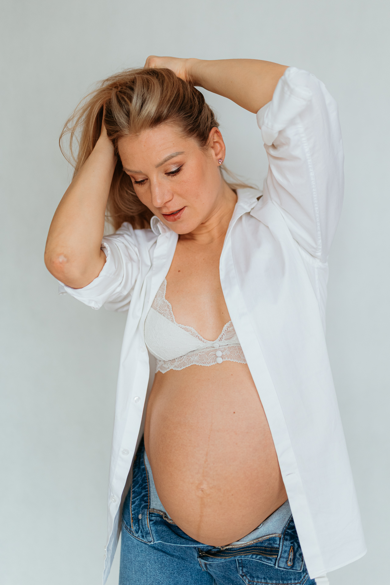 kobieta w białej koszuli z odsłoniętym brzuszkiem pozuje do zdjęcia w Krakowie